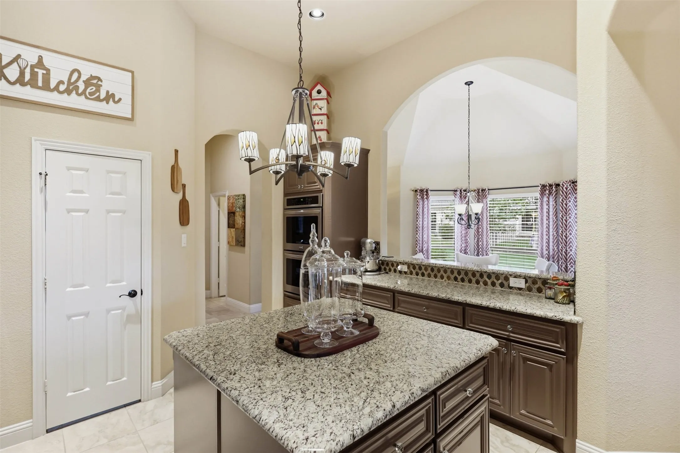 Kitchen featuring a central island with a light-toned countertop, recessed lighting, double wall ovens, and wood-finish cabinetry