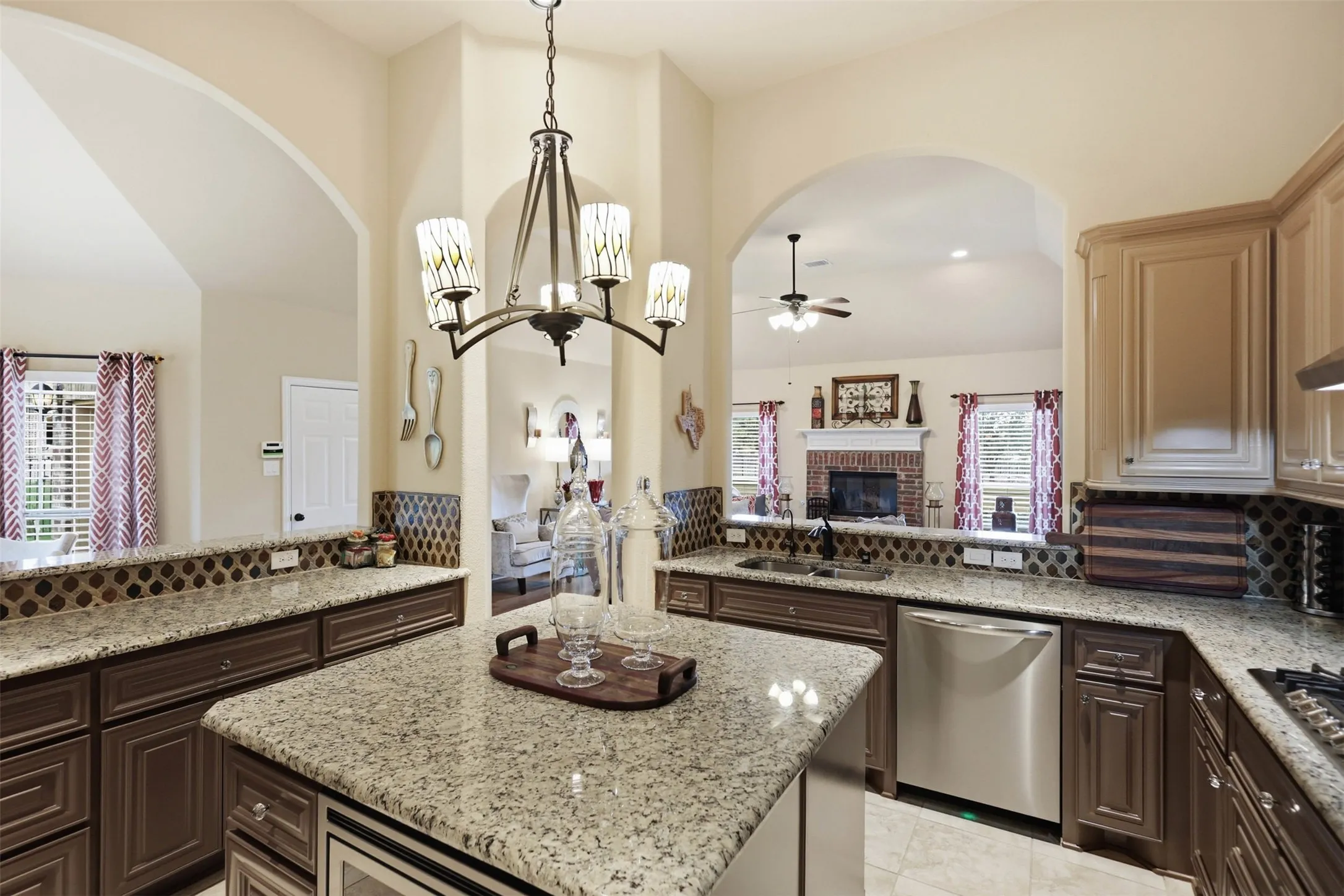 Expansive kitchen featuring a central island with a built-in microwave, stone countertops, and dark wood cabinetry