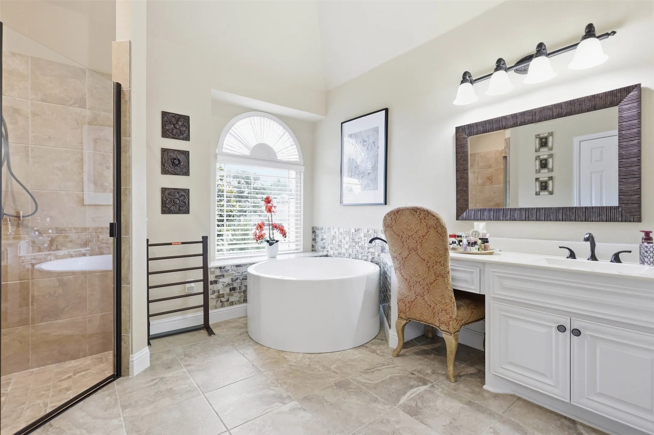 Spacious bathroom featuring a built-in soaking tub, separate glass-enclosed shower, a double vanity with a built-in makeup area, and large format tile flooring