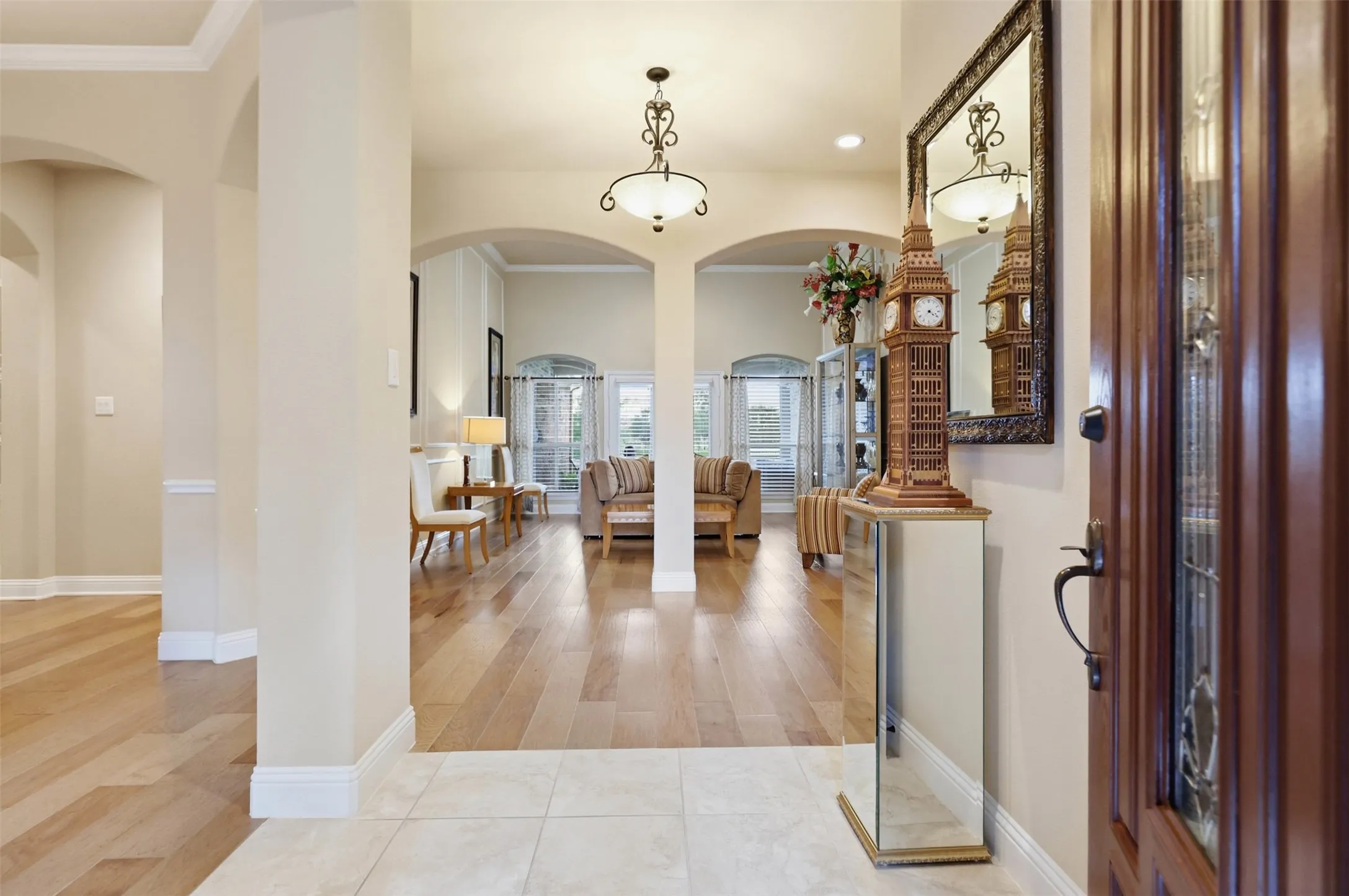 Entryway featuring light-toned tile flooring, a dark wood-finish door with decorative glass inserts, and an ornate framed wall mirror