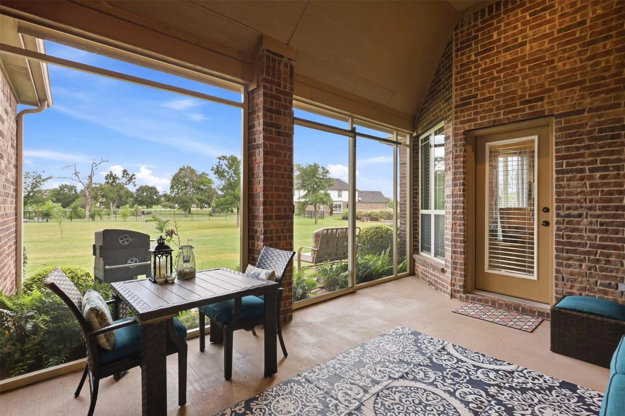 Screened patio featuring brick accents and a vaulted ceiling