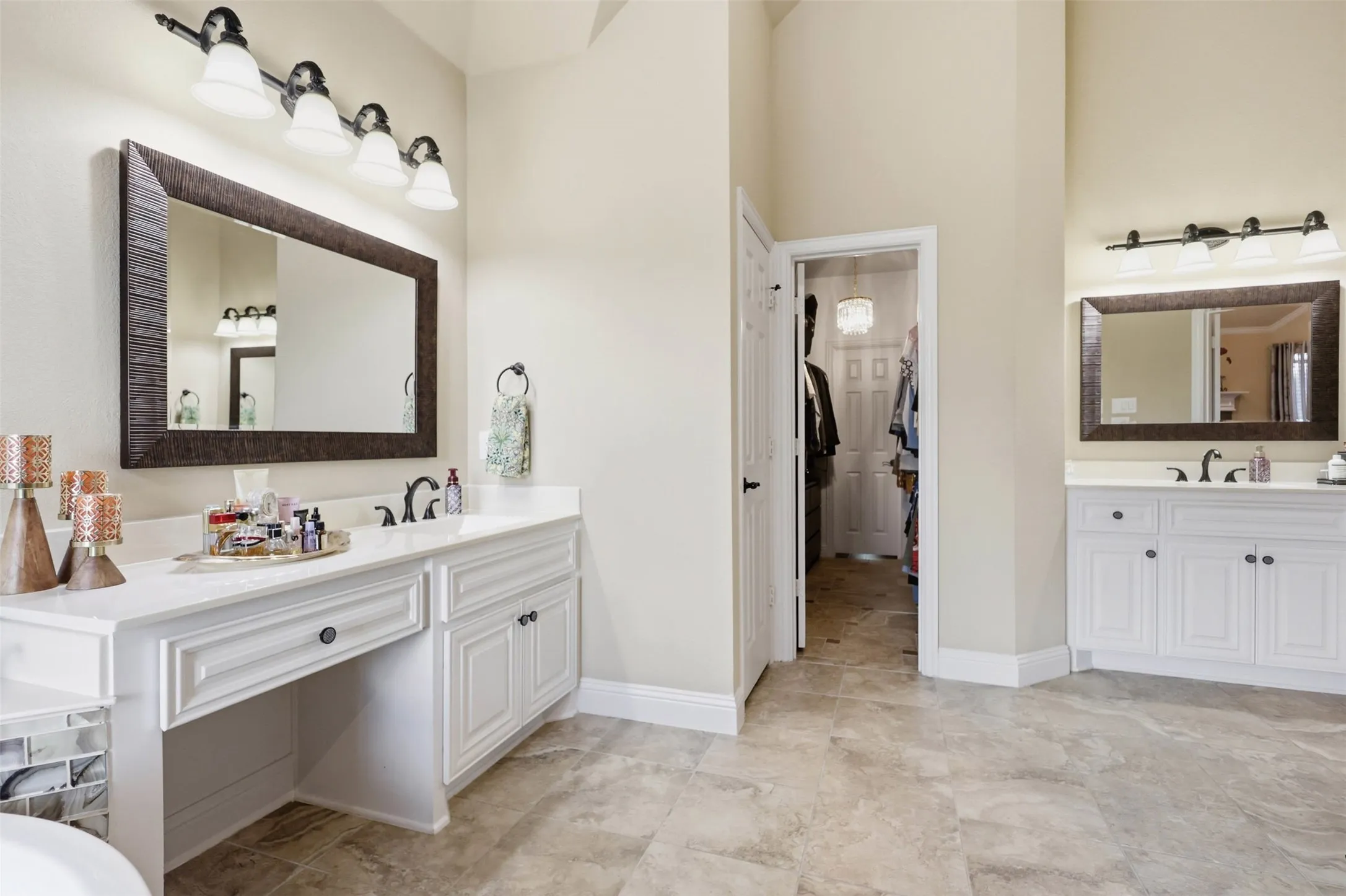 Spacious bathroom featuring twin white vanities with built-in cabinetry, individual sinks, and framed mirrors