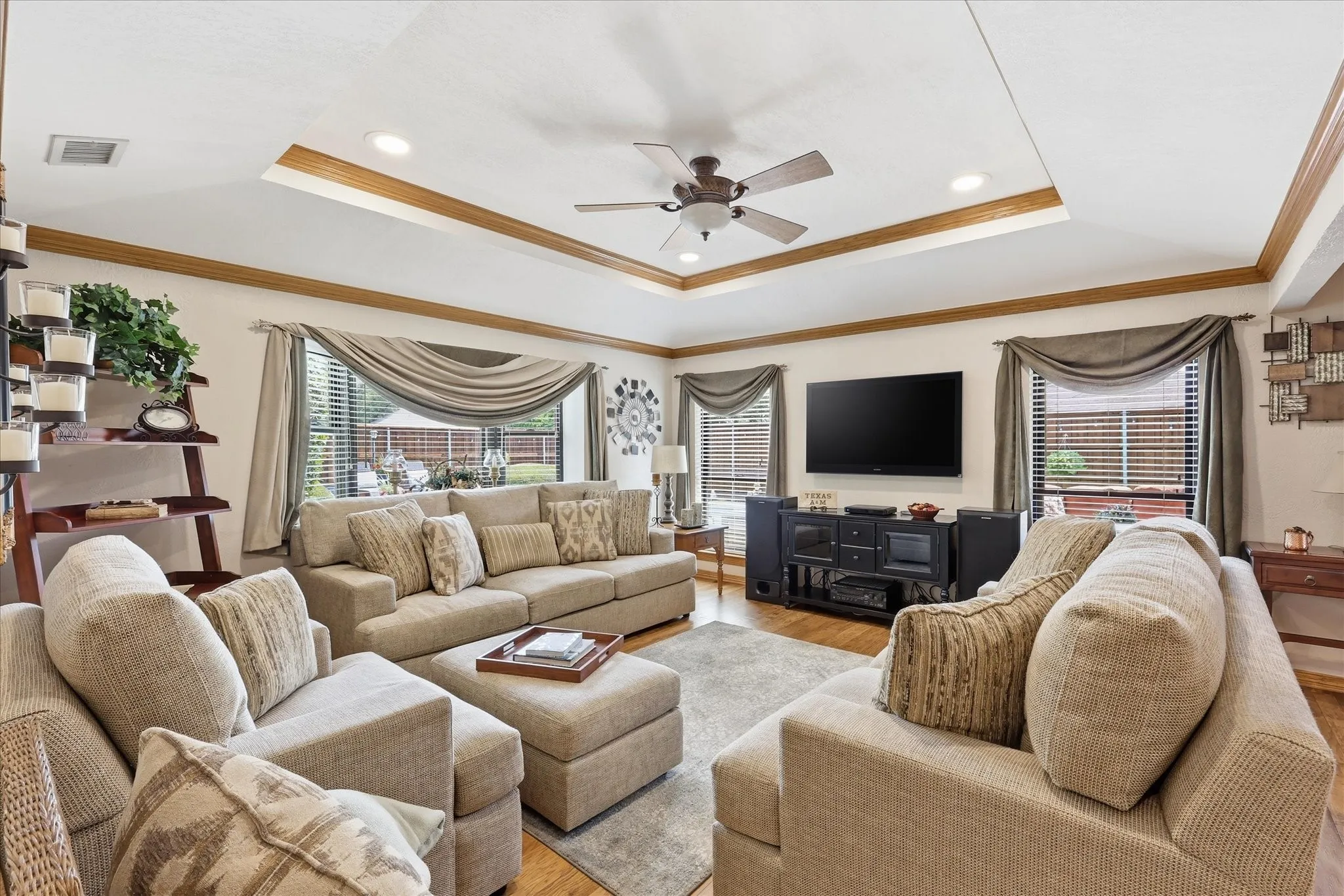 Spacious living area featuring a tray ceiling with wood-finish trim, recessed lighting, and a ceiling fan