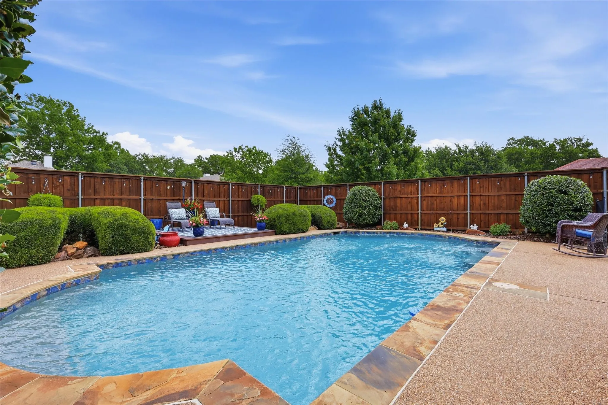 In-ground swimming pool with flagstone coping and an aggregate concrete deck