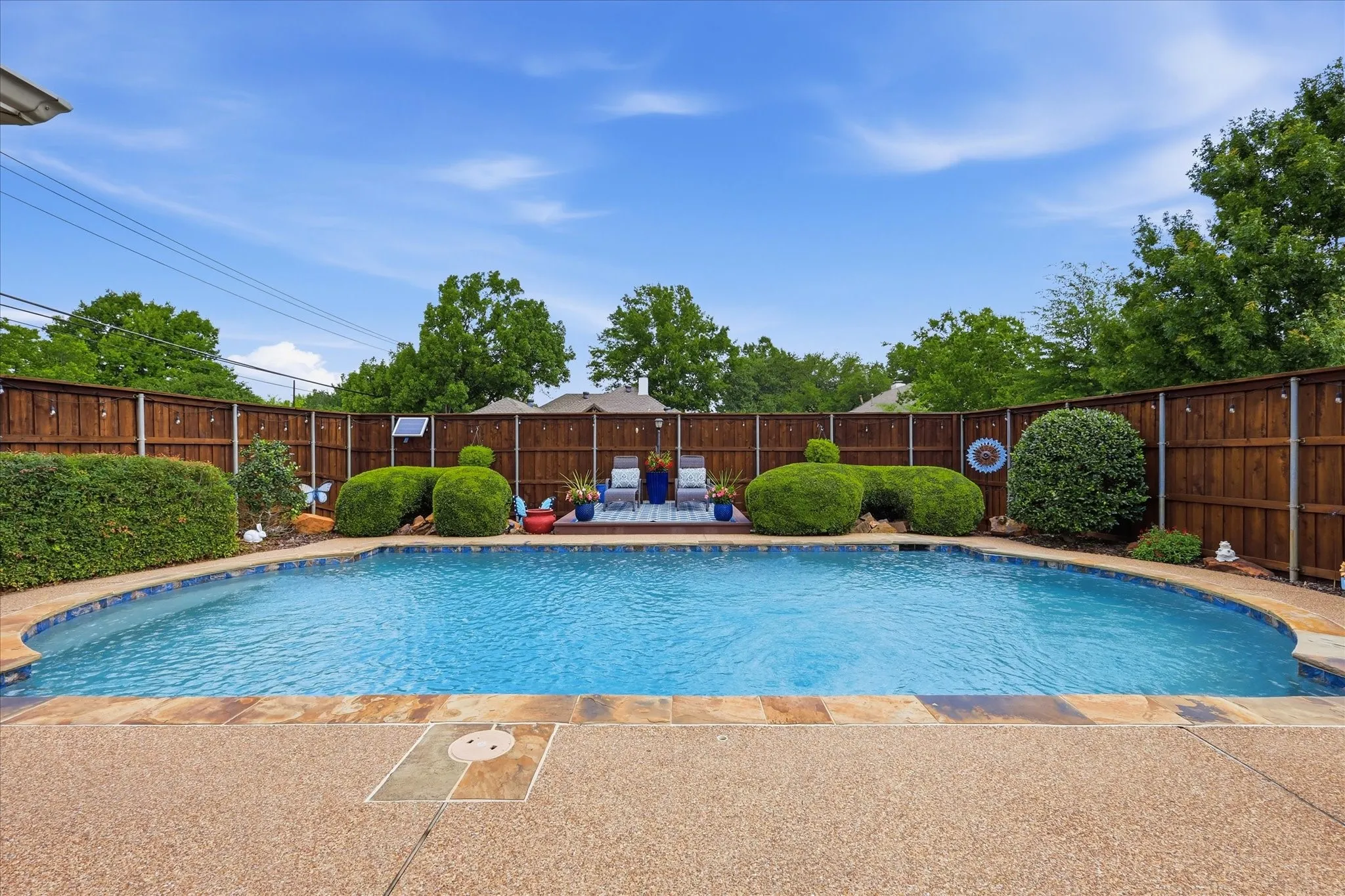 In-ground swimming pool with flagstone coping and an aggregate concrete surround