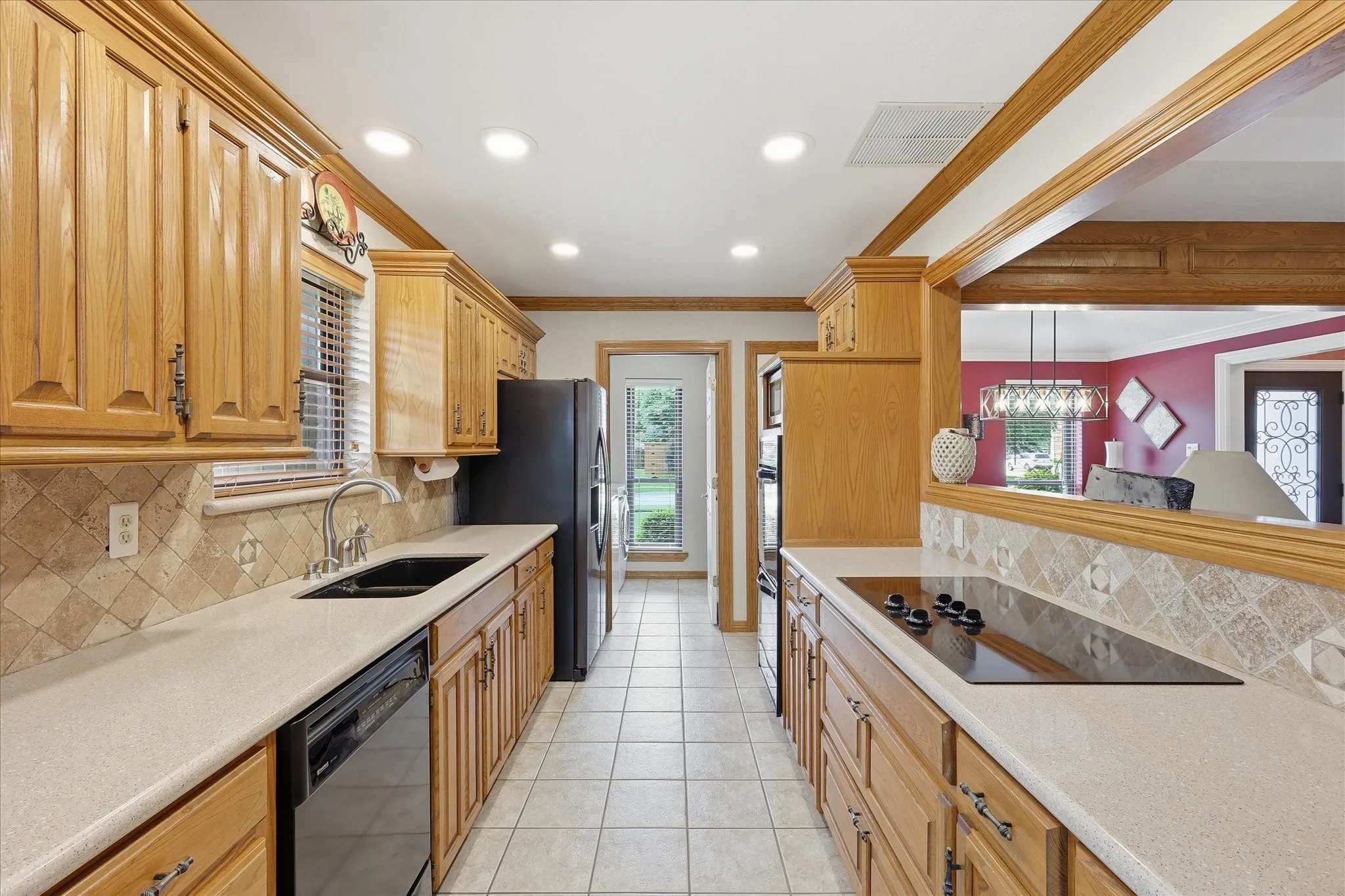 Galley kitchen featuring wood cabinetry, light-toned countertops, and a tiled backsplash