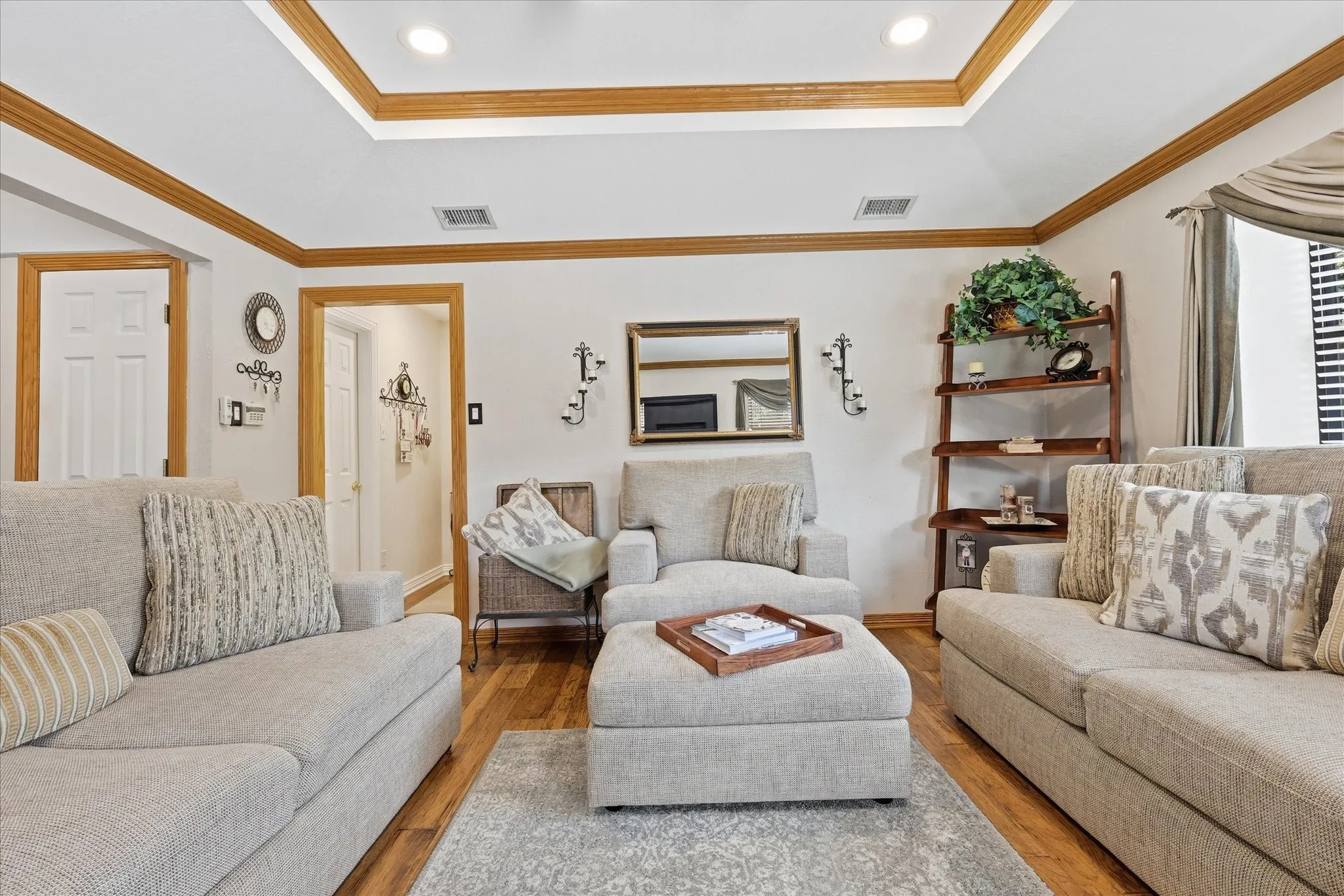 Living area featuring wood-finish flooring, a tray ceiling with recessed lighting, and warm wood trim