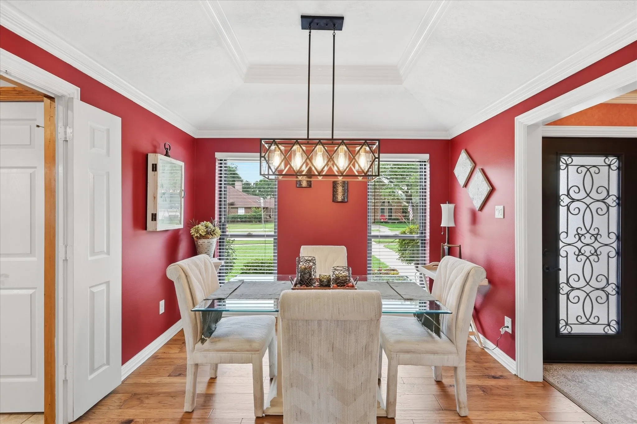 Dining area featuring wood-finish flooring, a tray ceiling with crown molding, and a modern rectangular chandelier