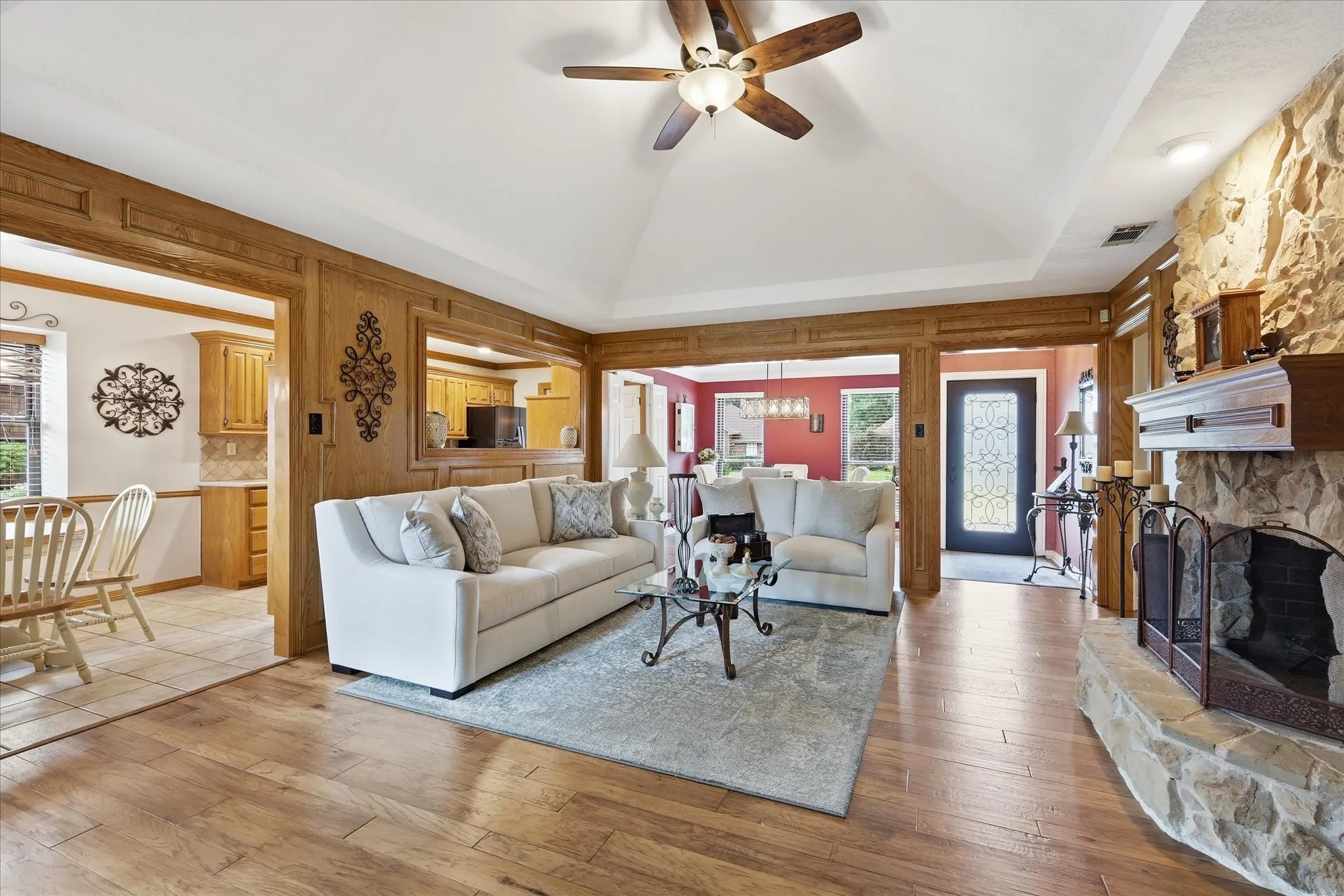 Living area featuring wood-finish flooring, a vaulted ceiling, and a stone-clad fireplace