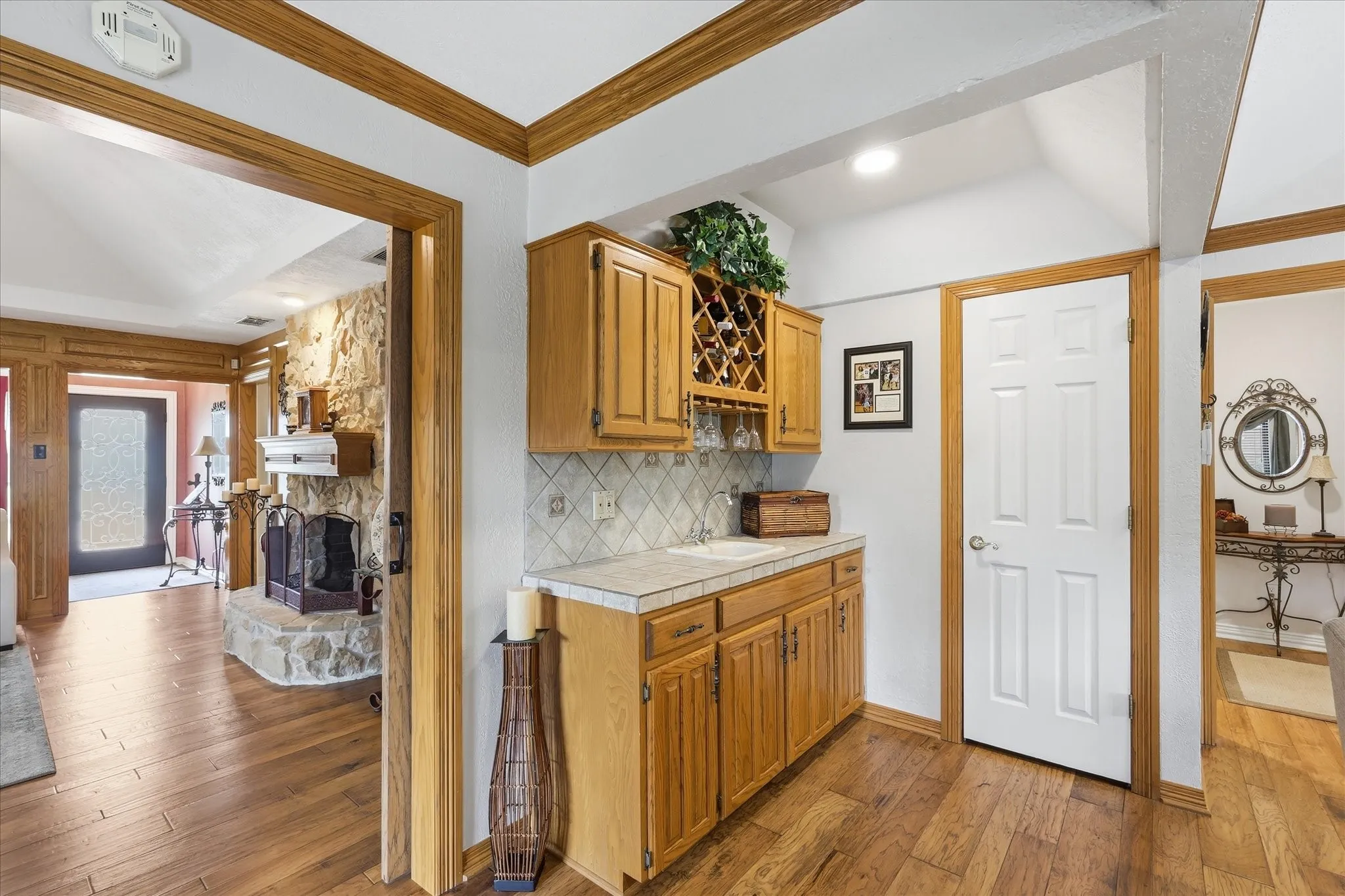 Built-in wet bar featuring wood cabinetry, integrated wine rack, and tile countertop with a single basin sink