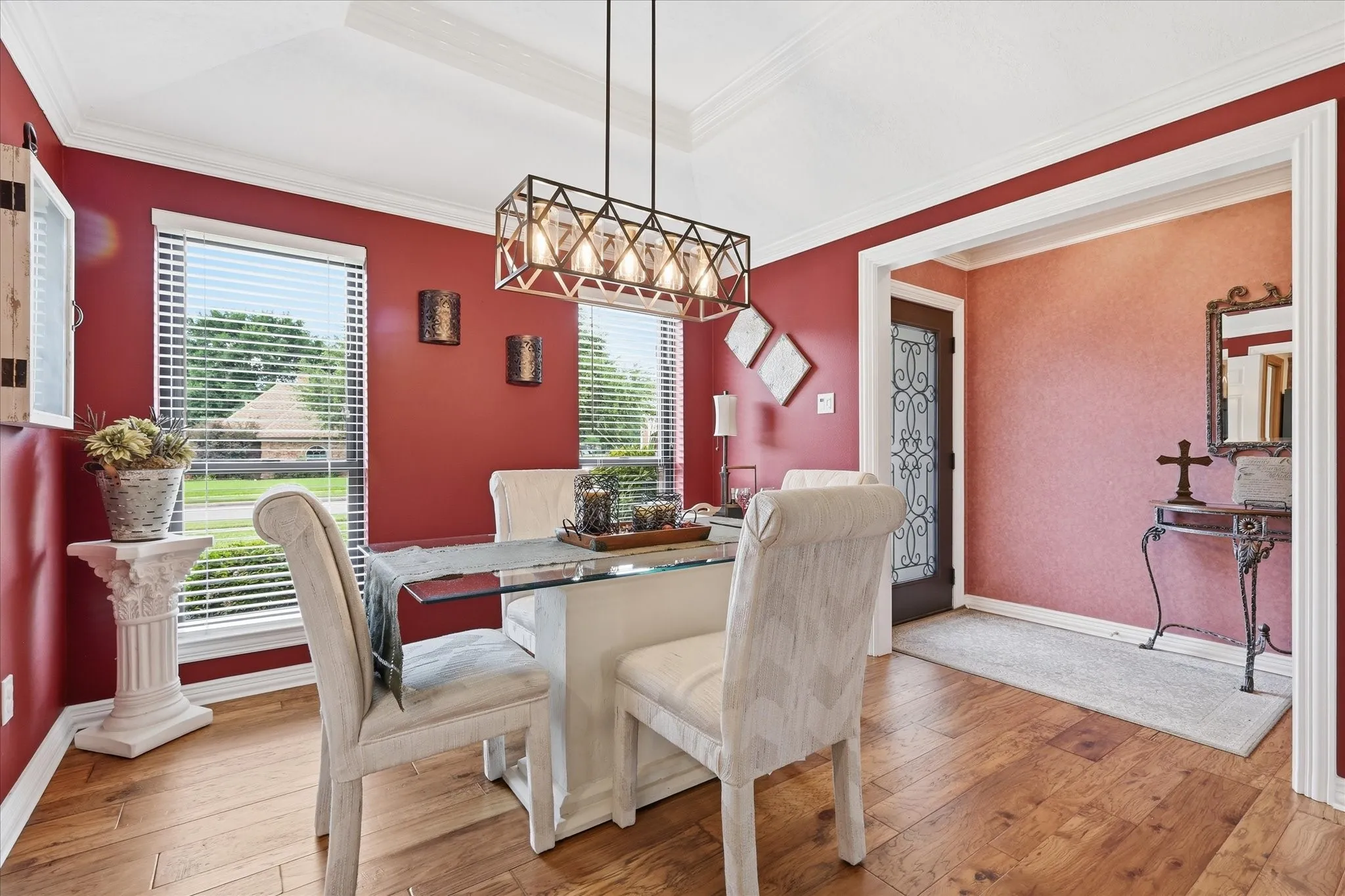 Dining area featuring wood-finish flooring, a tray ceiling, and a modern linear chandelier