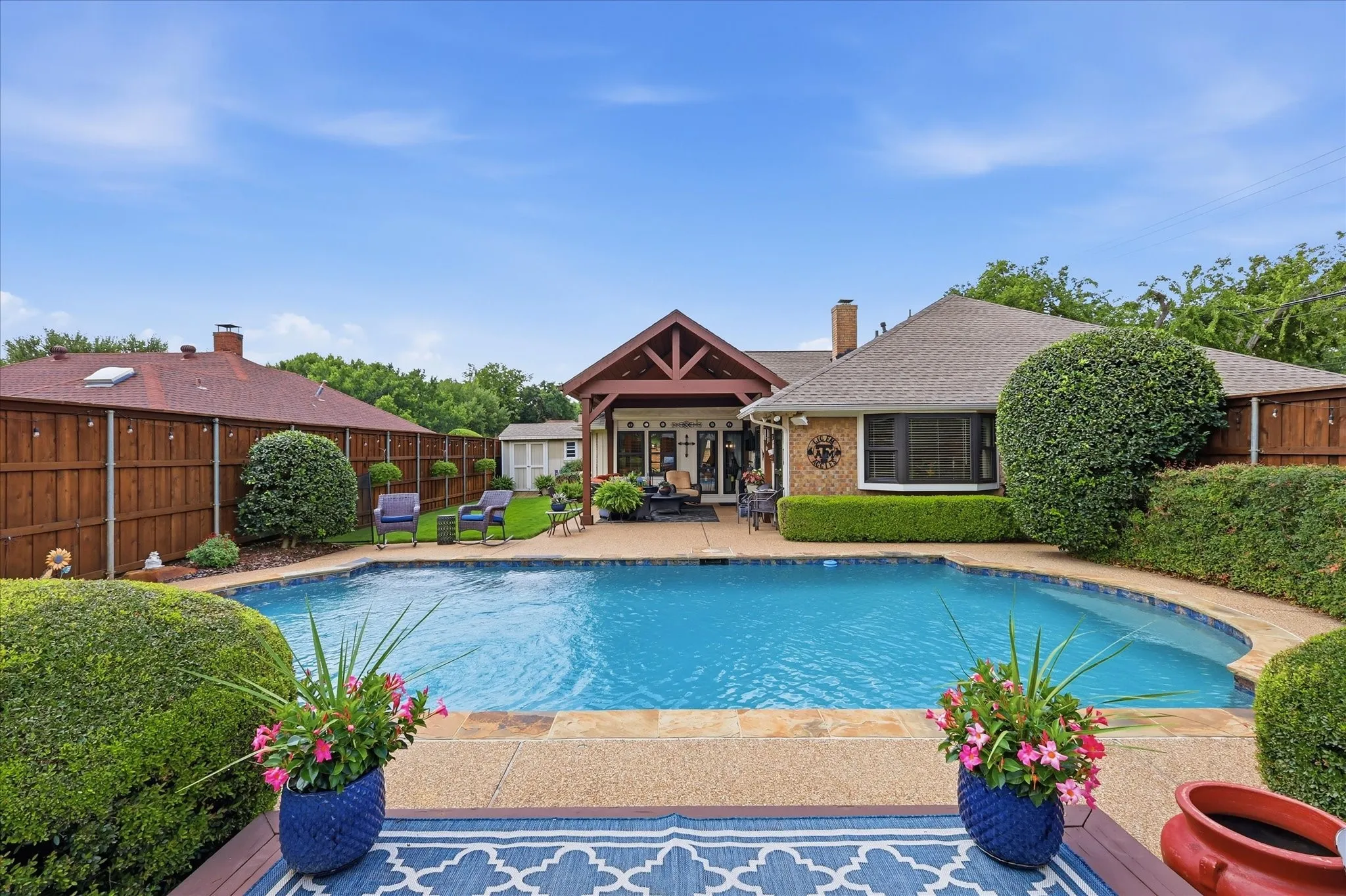 Curved swimming pool with an exposed aggregate concrete deck and integrated water features