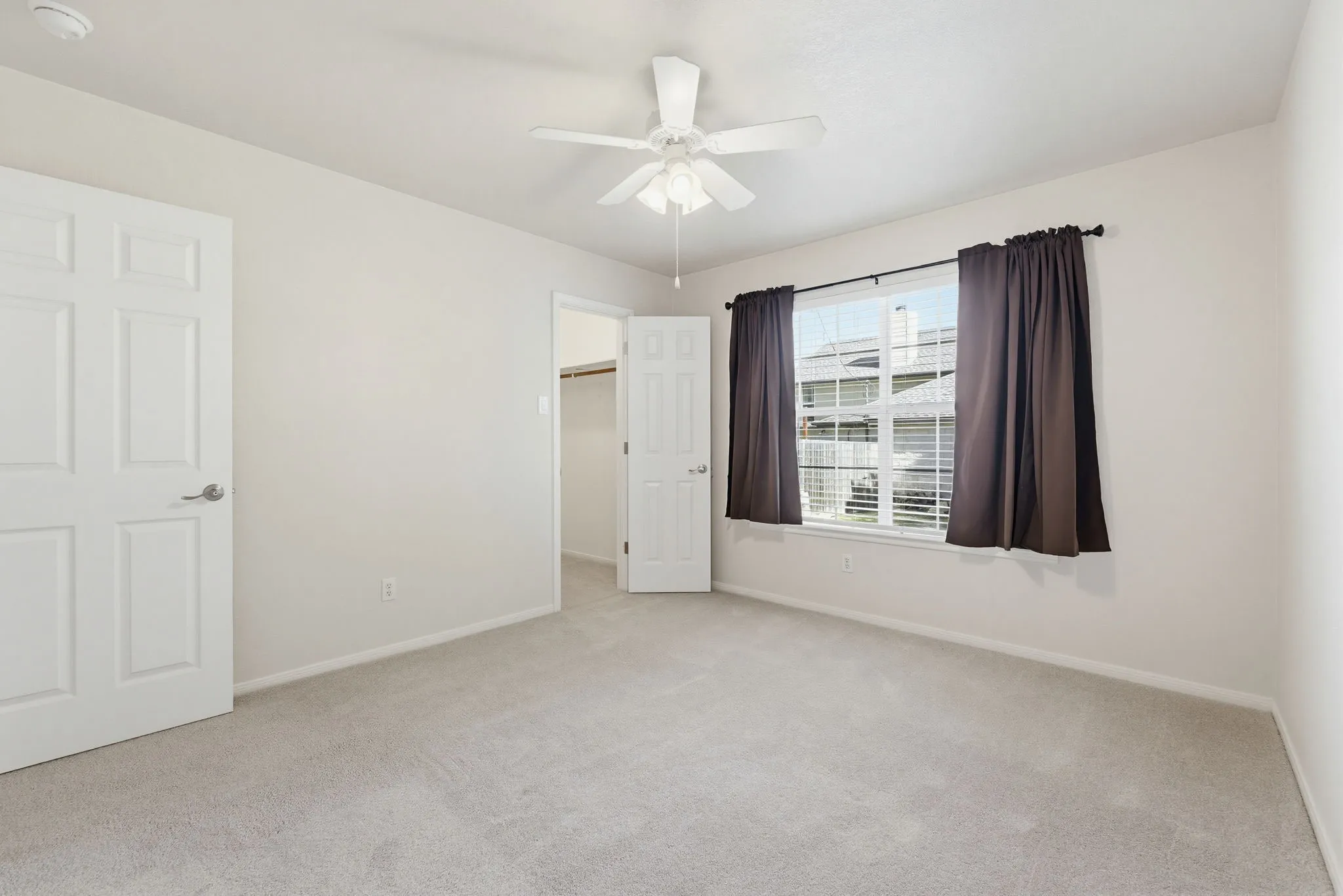 Carpeted room featuring a ceiling fan with integrated lighting, a window with blinds, and two panel doors
