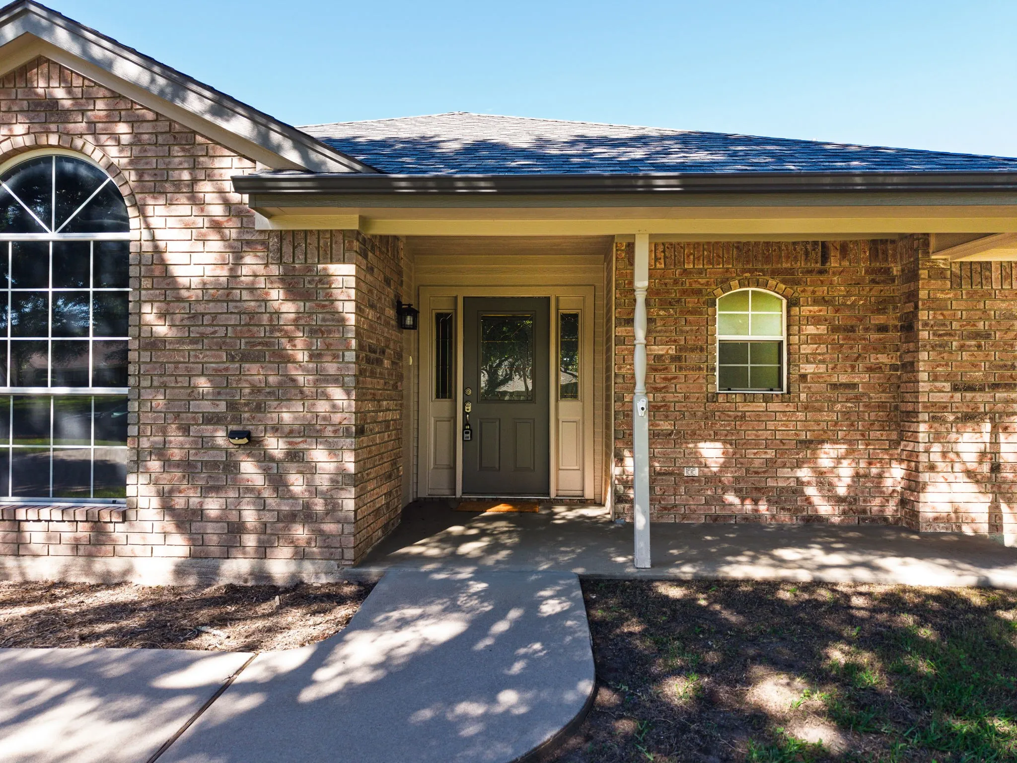 Brick exterior featuring a covered front porch with a white column