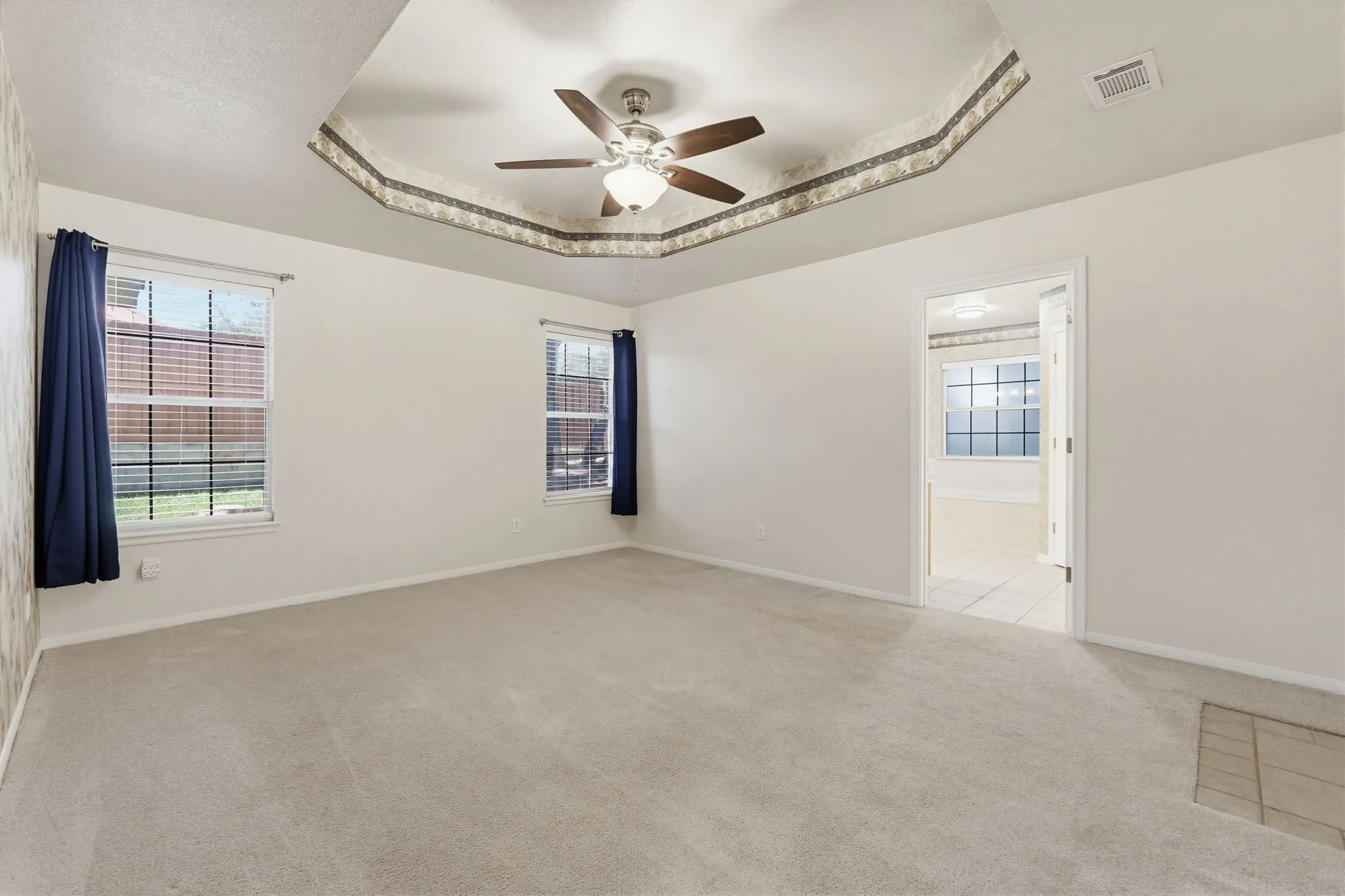 Spacious room featuring a tray ceiling with decorative trim and a ceiling fan