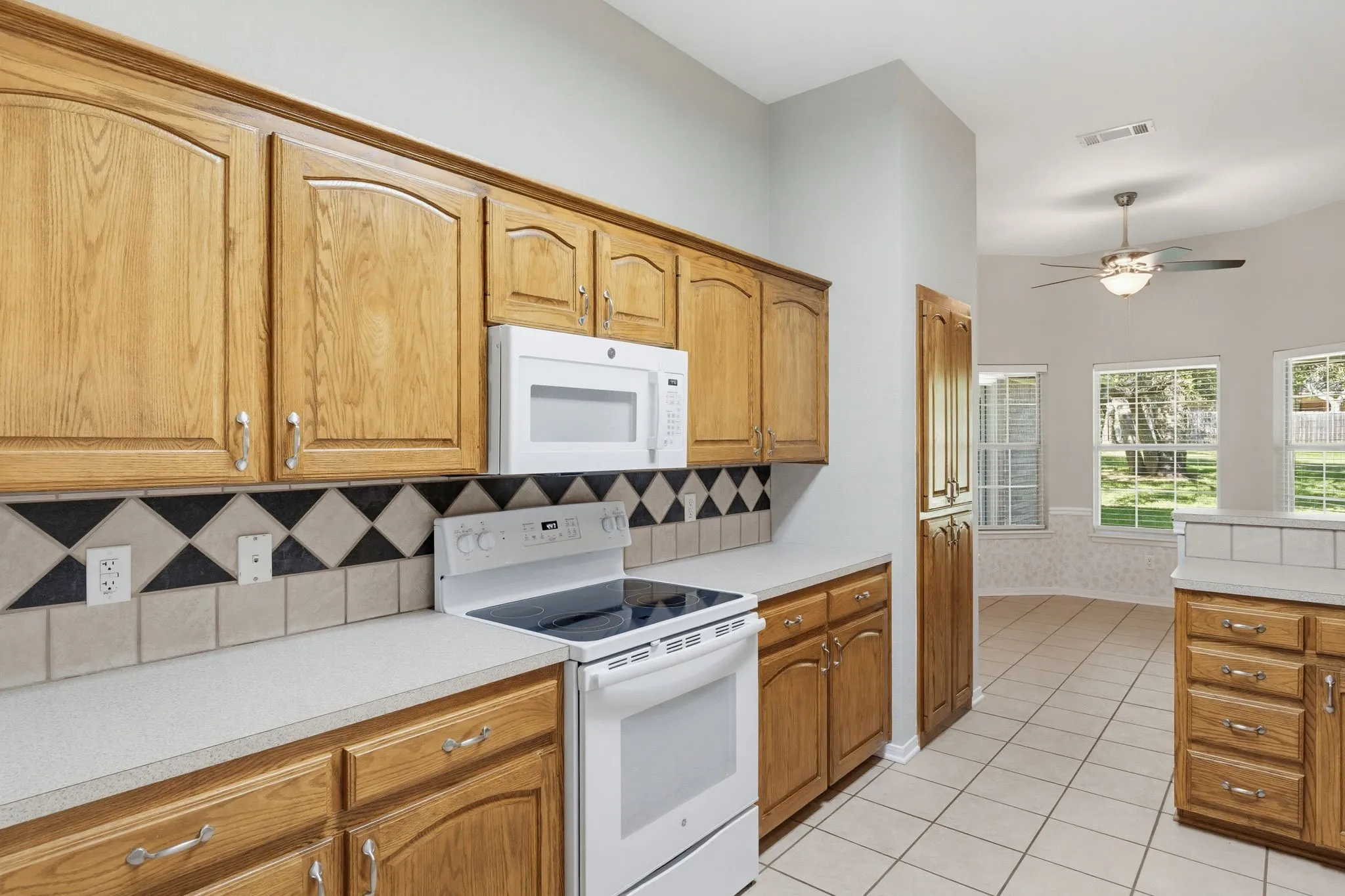 Kitchen featuring wood cabinetry, white appliances, and a tiled backsplash