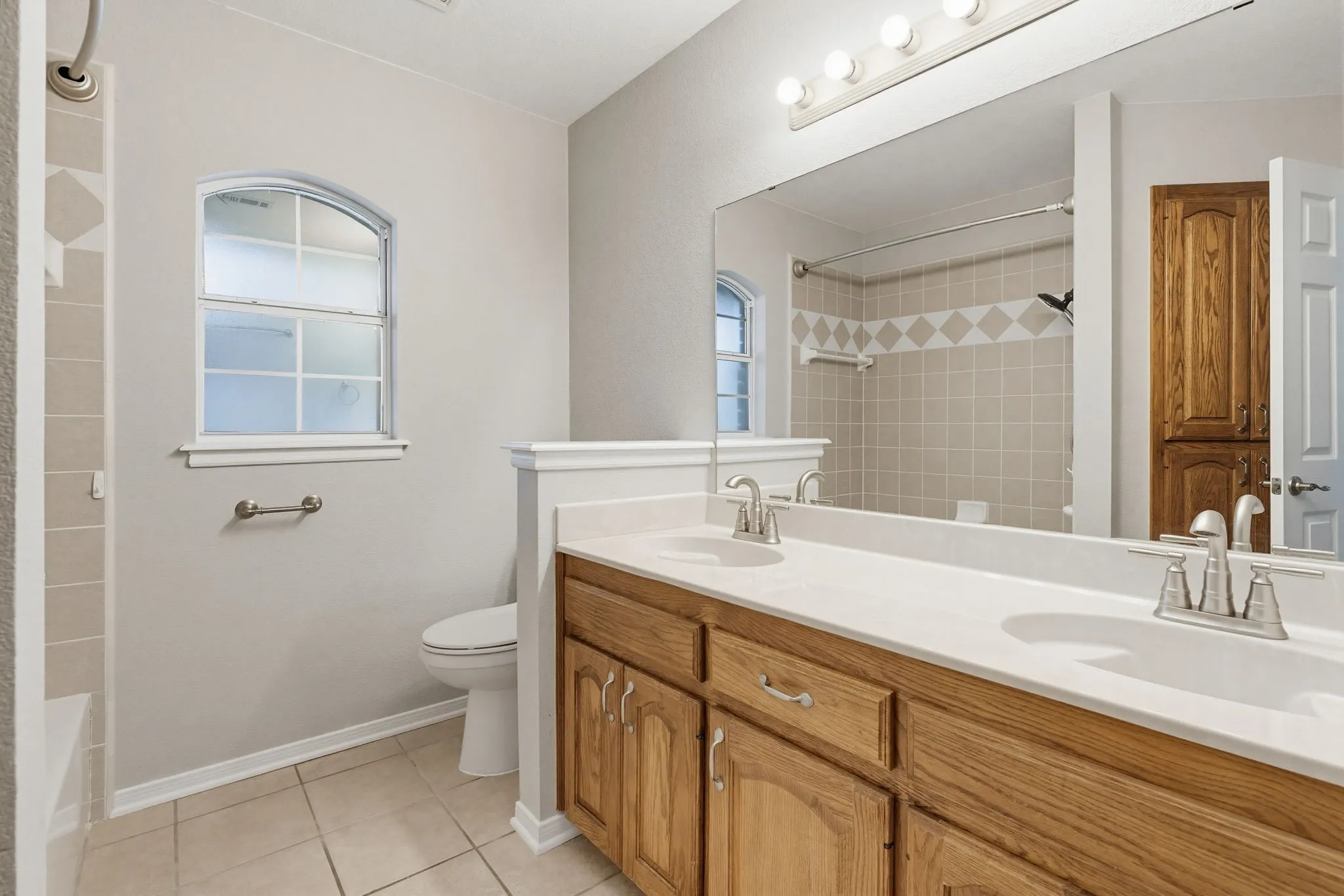 Double vanity with light countertops and wood-finish cabinetry