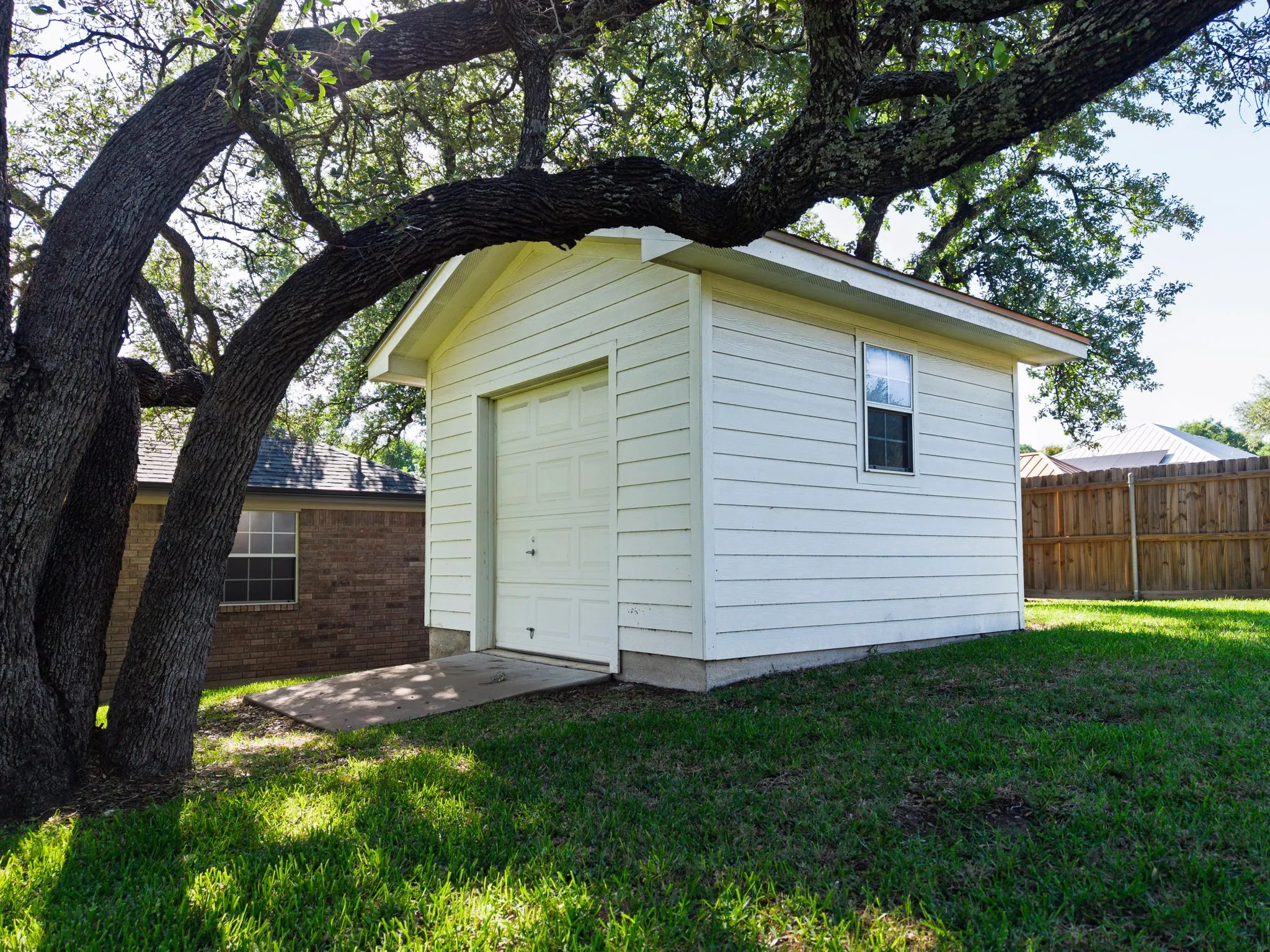 Freestanding utility building with horizontal siding, a roll-up door, and a single window