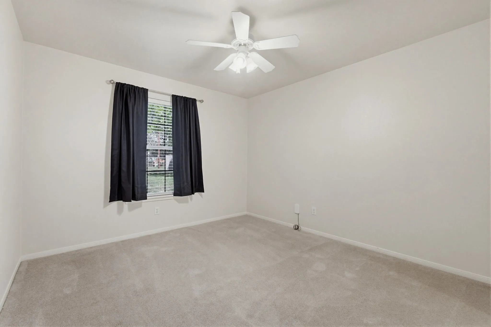 Carpeted room with a single window featuring horizontal blinds and dark drapery panels