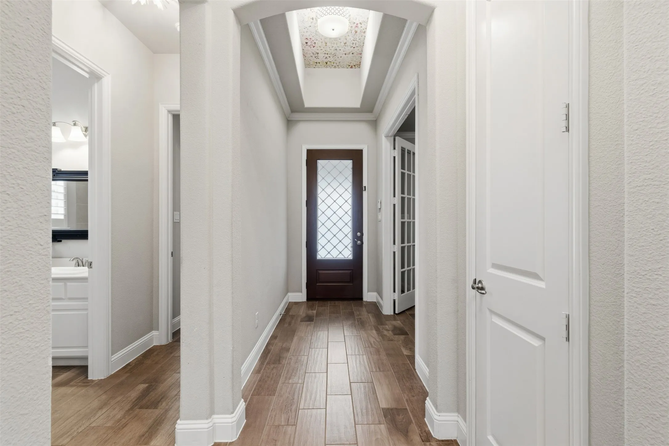 Foyer featuring wood-finish tile flooring, an arched entryway, and a dark wood front door with decorative glass