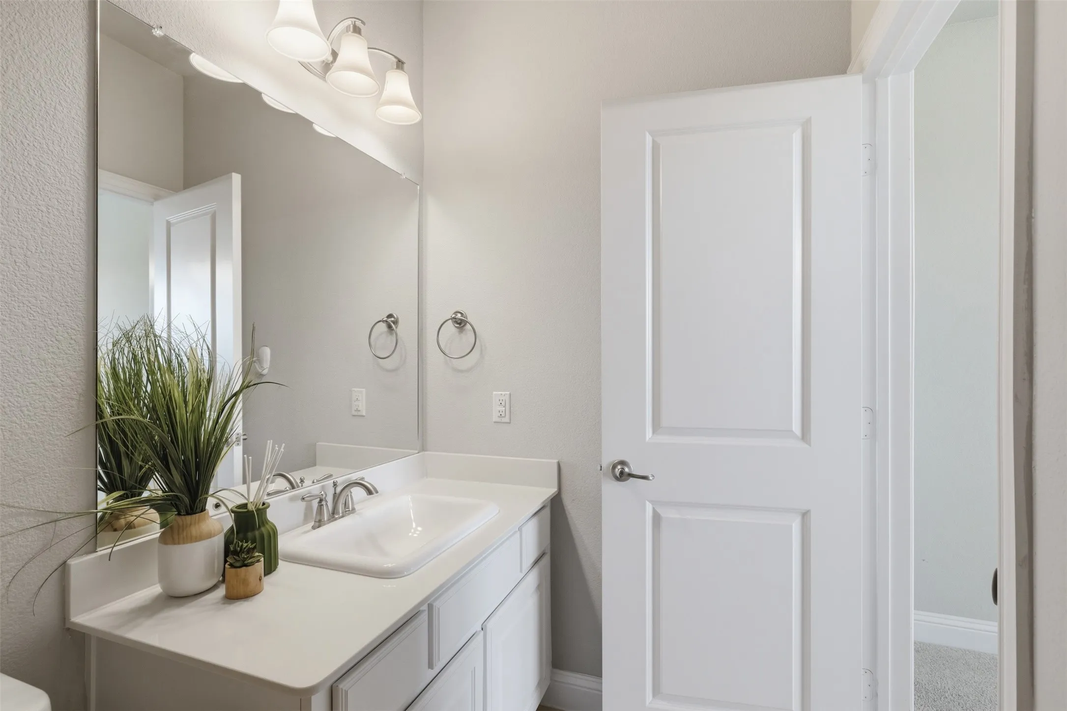 Bathroom vanity featuring a white countertop with an integrated sink, brushed nickel faucet, and a large wall-mounted mirror