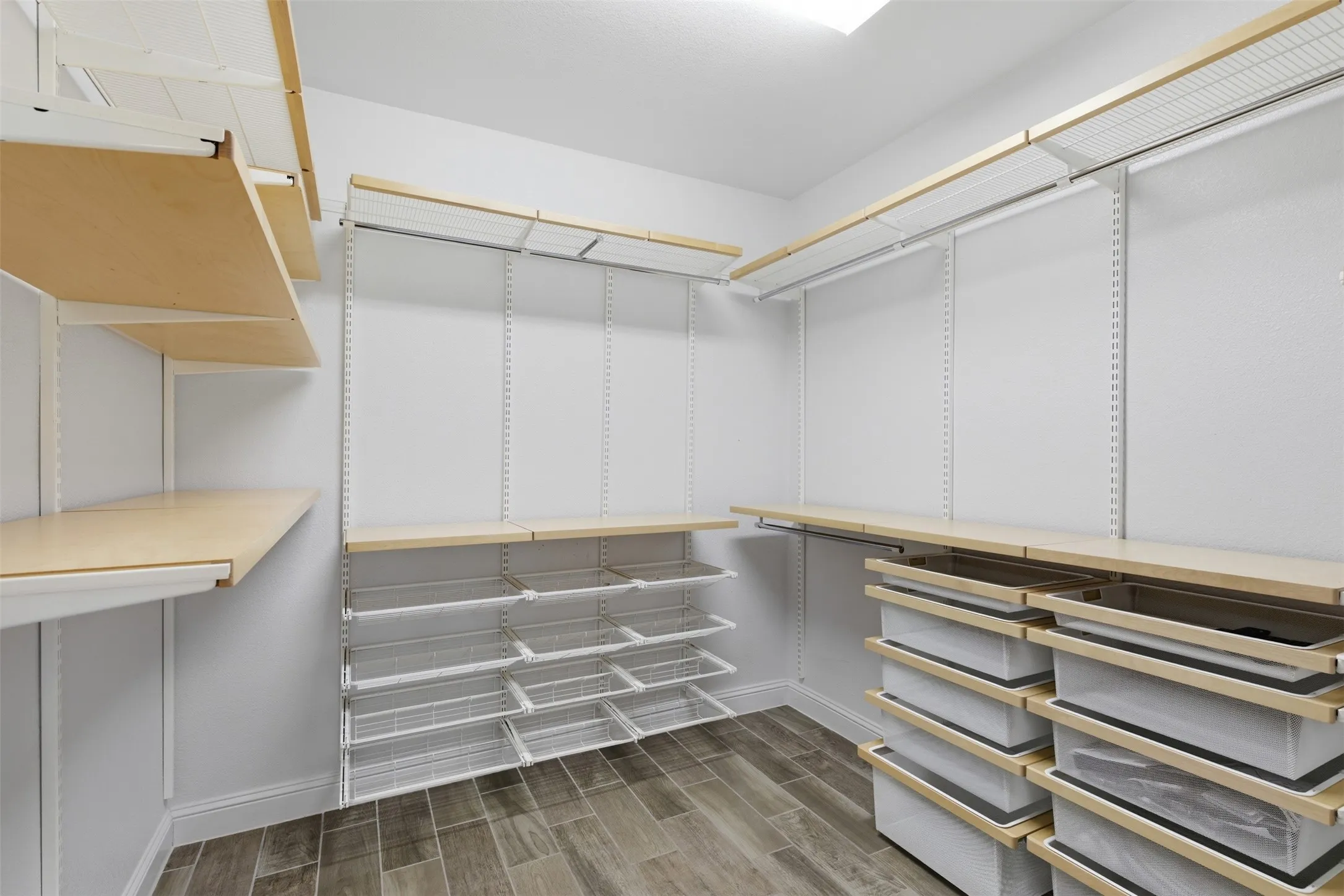 Walk-in closet featuring wood-finish shelving and wire baskets, wire rack storage, wood-finish flooring, and recessed lighting