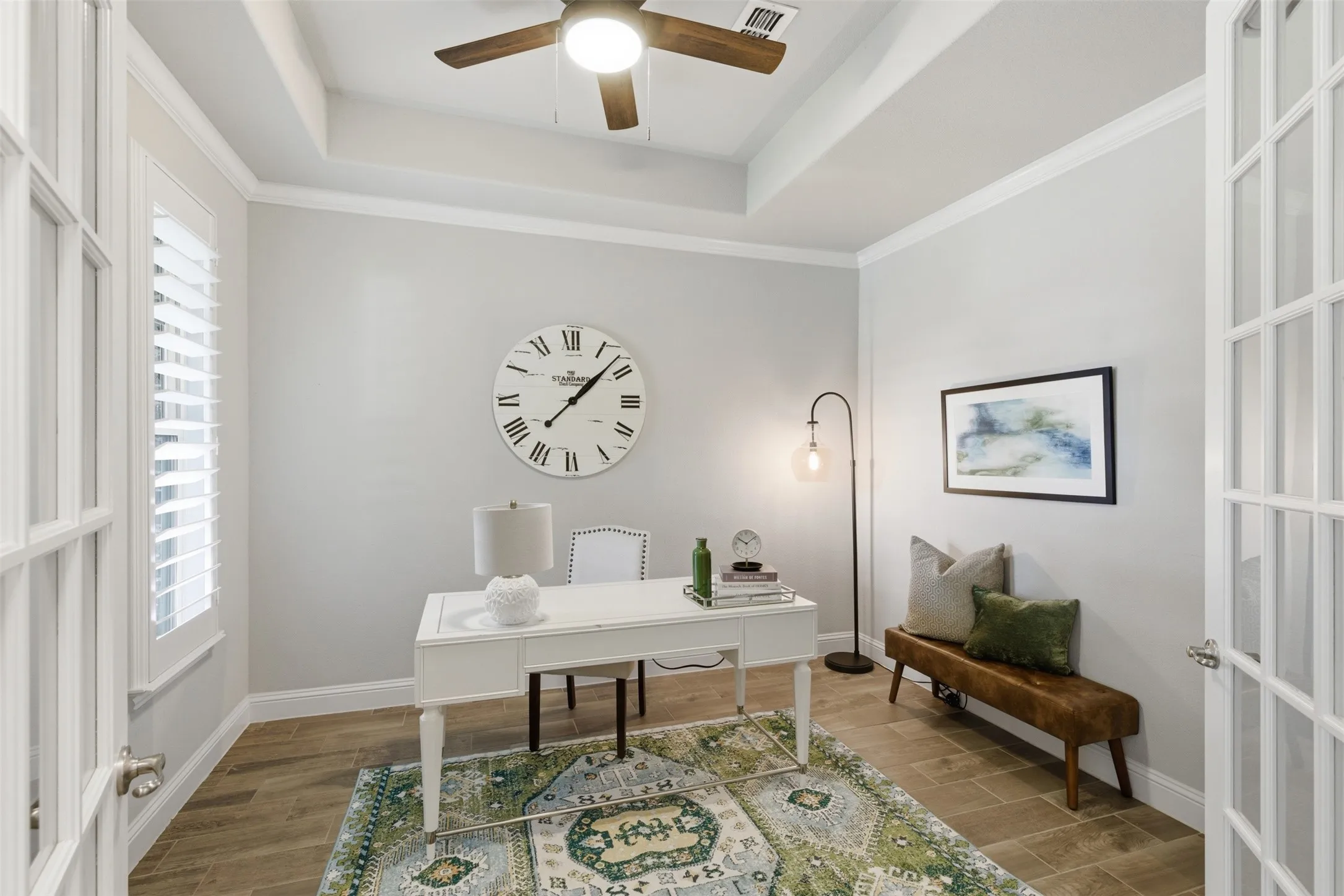 Room with wood-finish flooring, white walls, and a tray ceiling