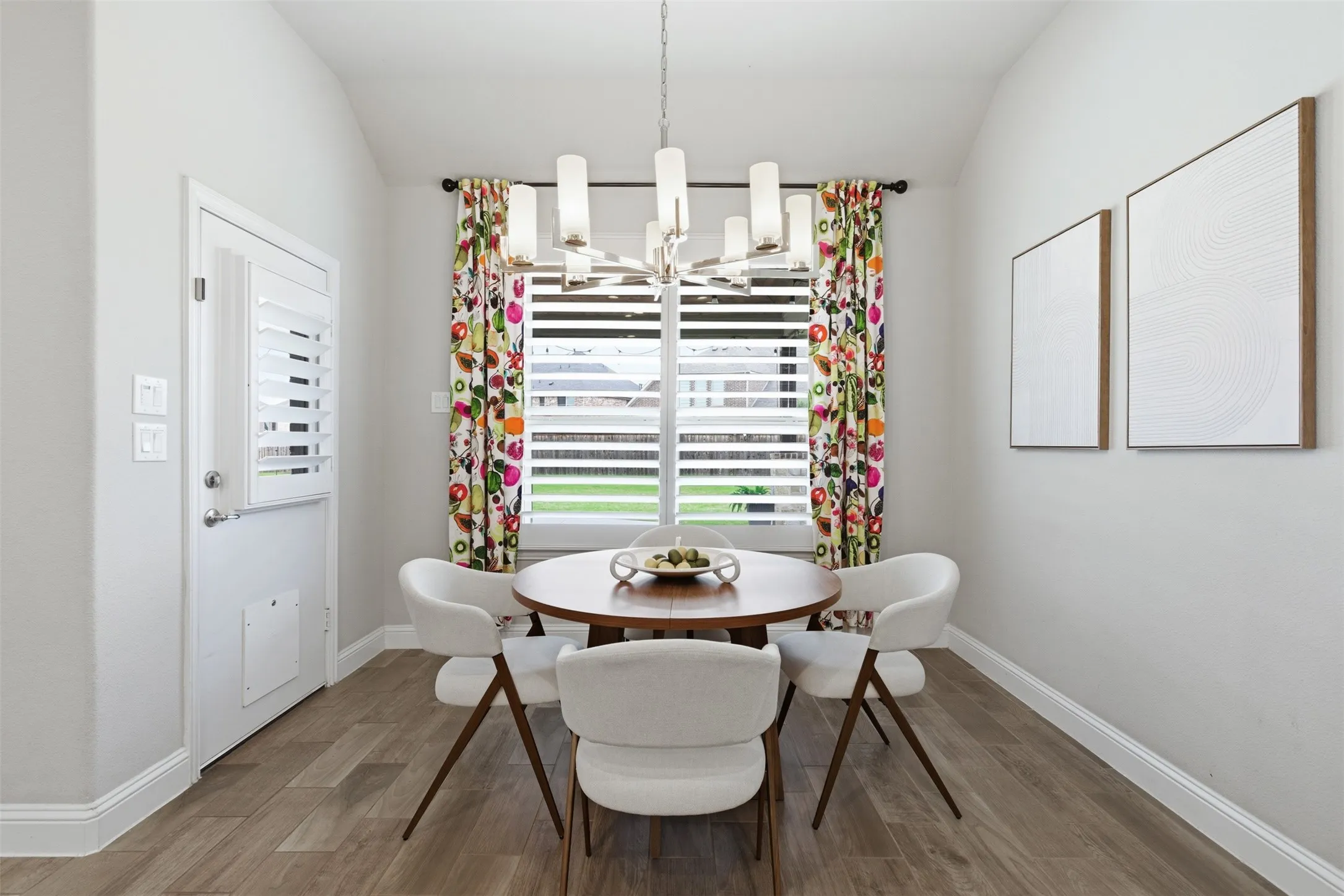 Dining area featuring wood-finish flooring, a contemporary chandelier, and a window with plantation shutters