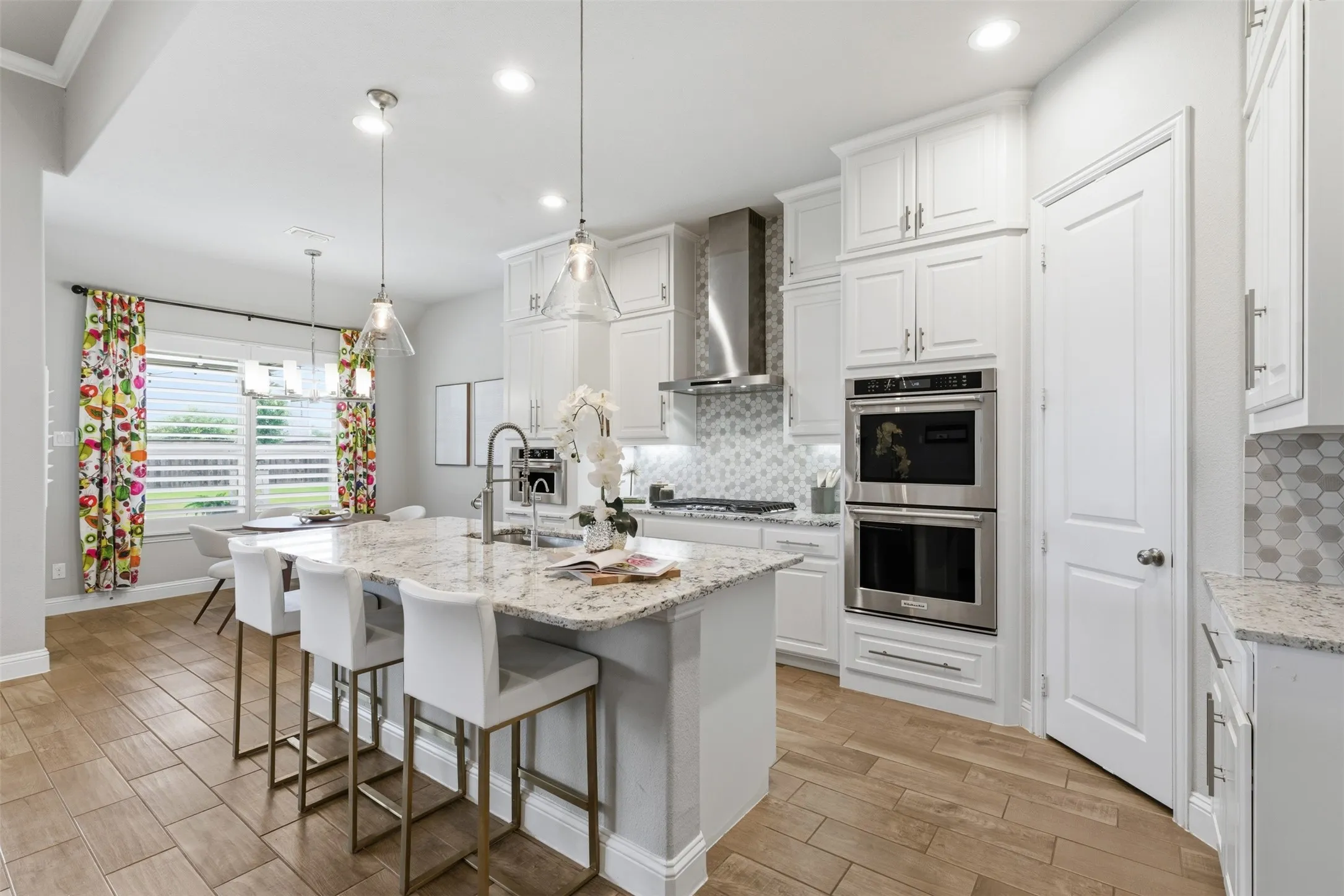 Modern kitchen with wood-finish tile flooring and an oversized island featuring a light-toned countertop