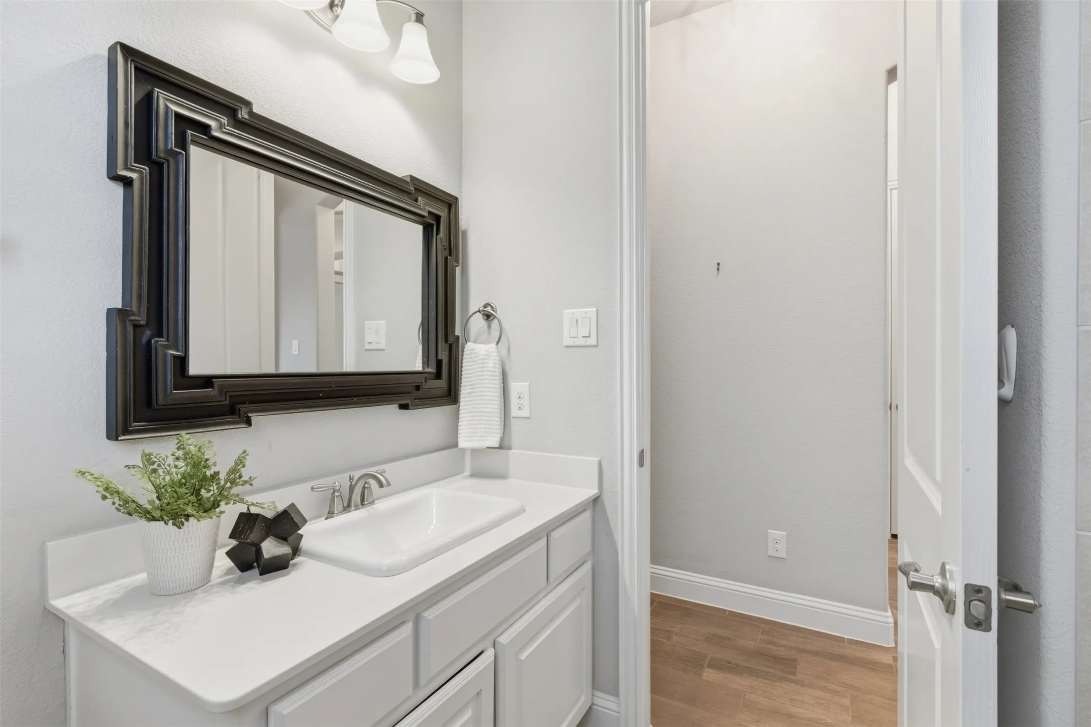 First floor secondary bathroom vanity featuring a white countertop, undermount sink with chrome faucet, and white cabinetry