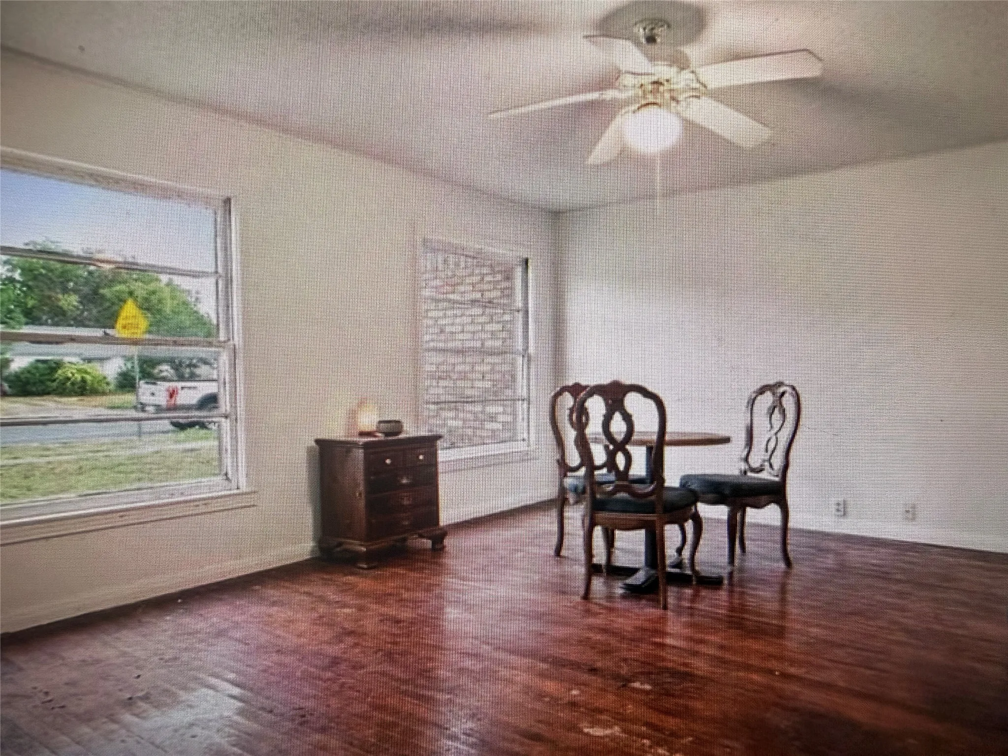 Bright interior space featuring wood-finish flooring, multiple windows, and a ceiling fan with integrated lighting