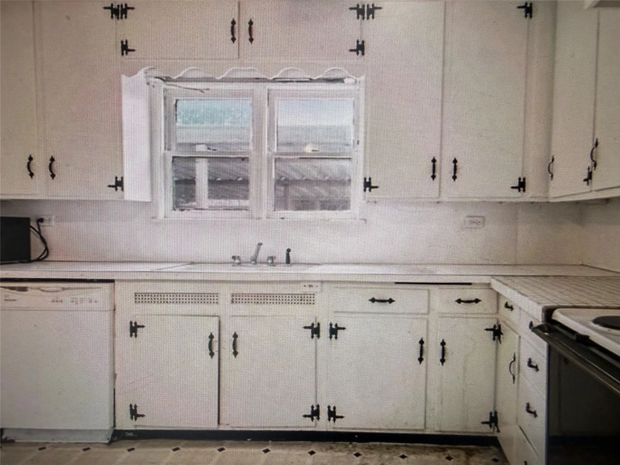 Kitchen featuring white cabinetry with black hardware, a dual-basin sink, and a window above