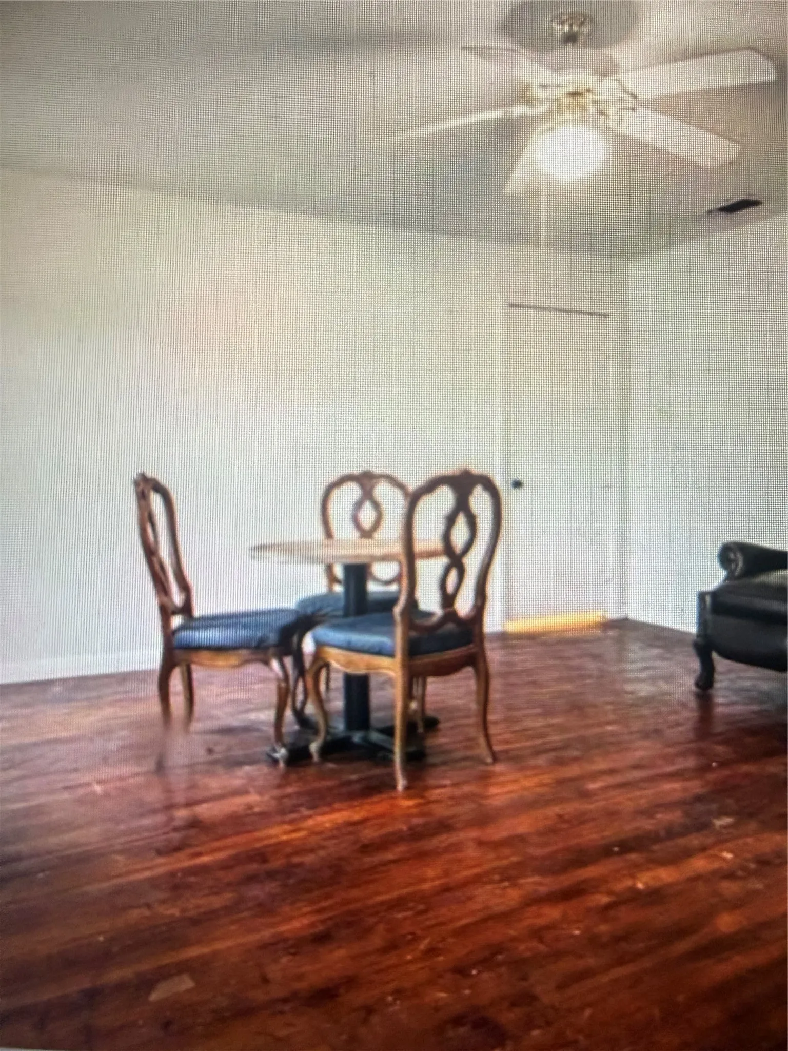 Expansive room featuring wood-finish flooring, white painted walls, and a ceiling fan with integrated lighting