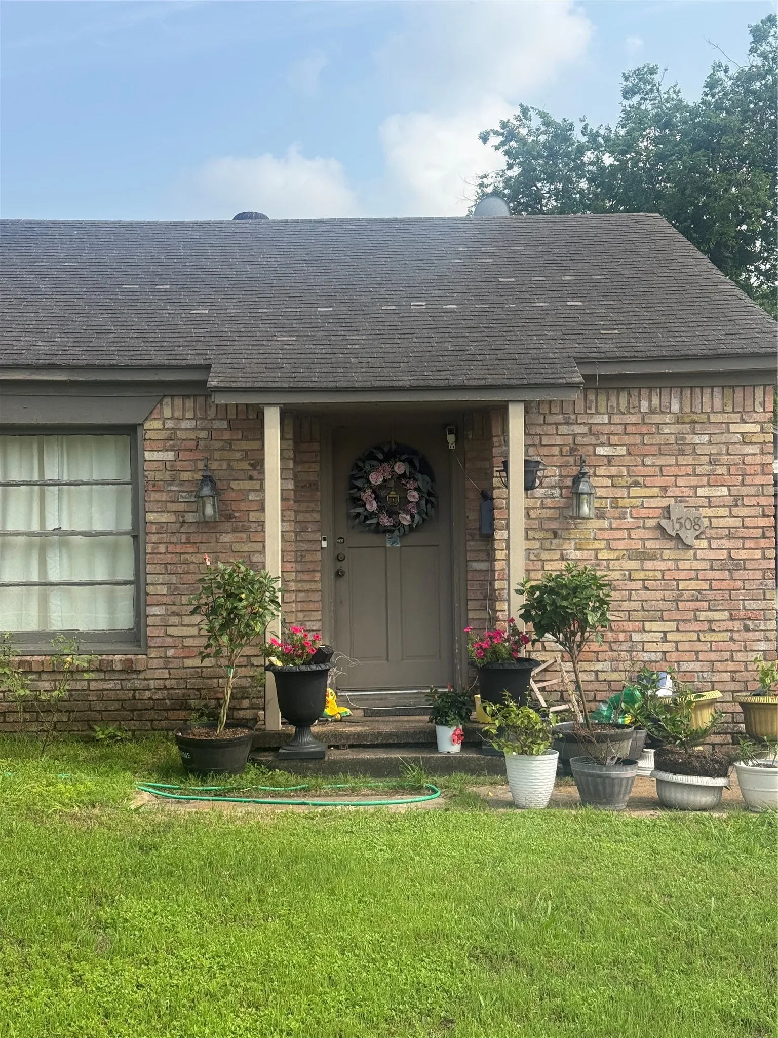 Brick exterior home featuring a covered entryway, a gabled roofline, and exterior wall sconces