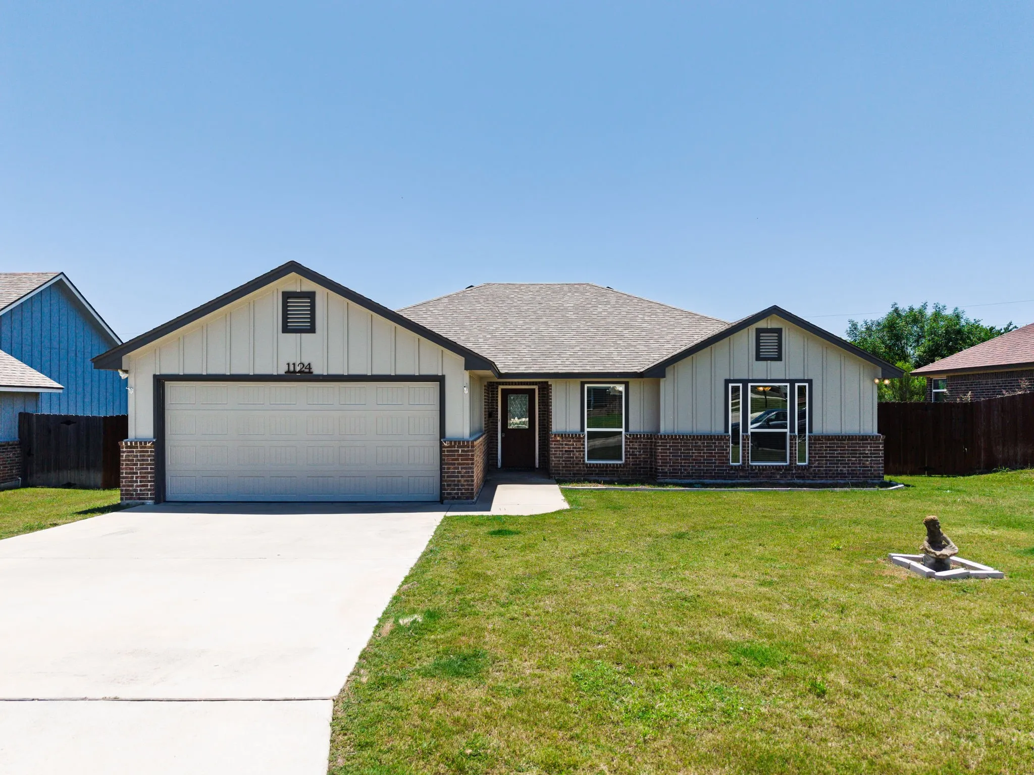 Single-story residence featuring a brick and vertical siding exterior, an attached two-car garage, a concrete driveway, and a front walkway
