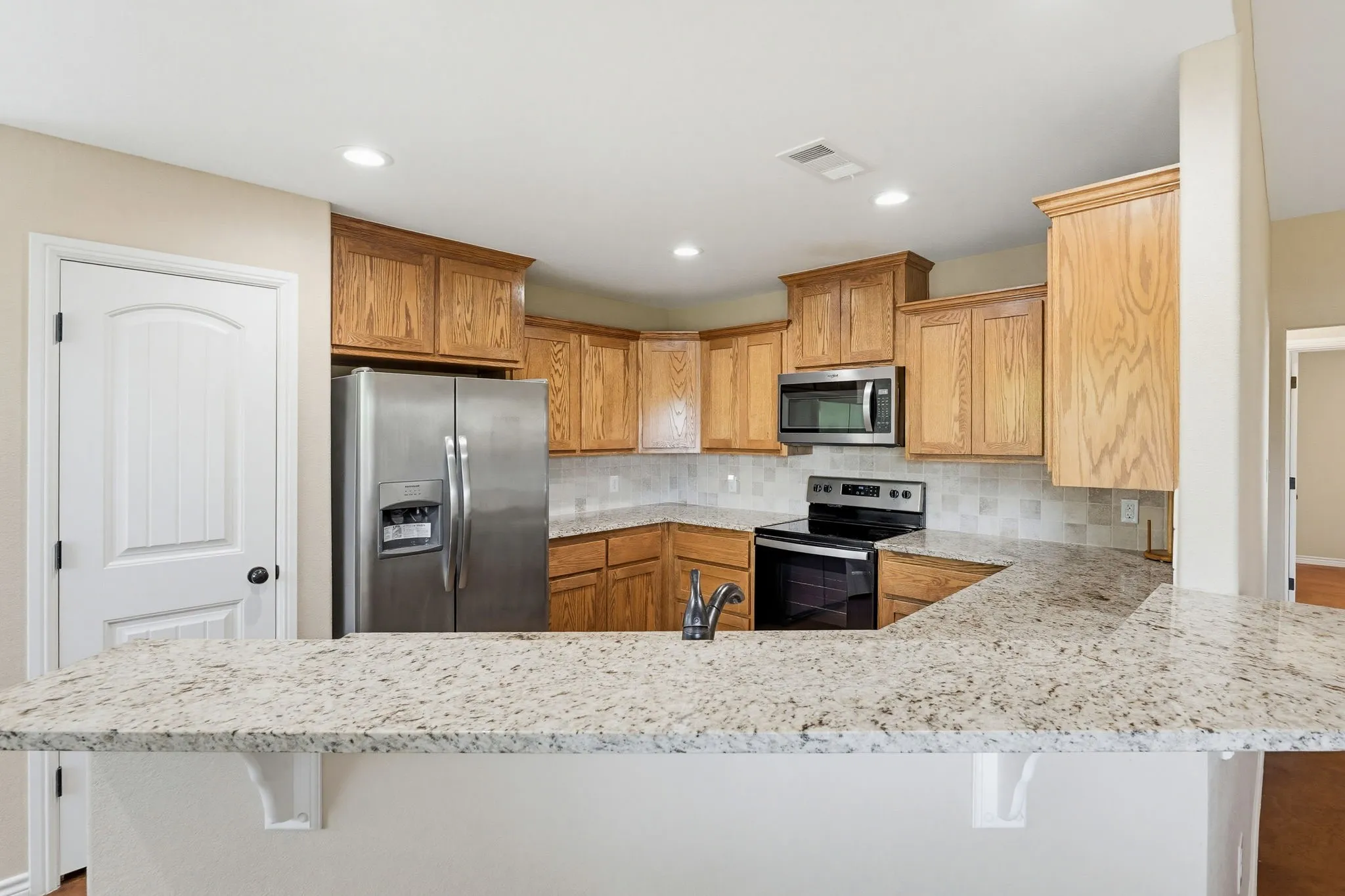 Kitchen featuring wood cabinetry, stainless steel appliances, a tile backsplash, and light-toned countertops
