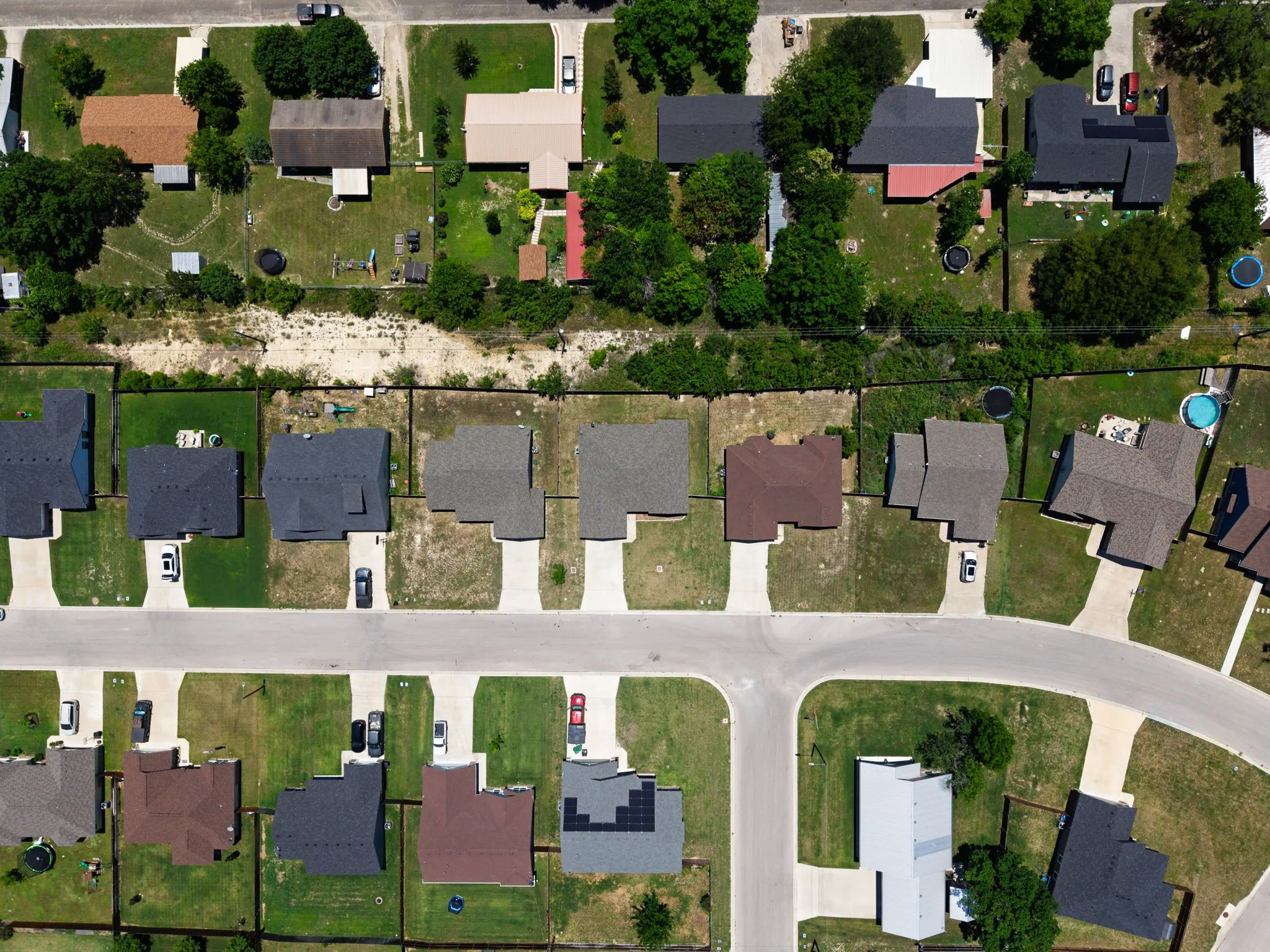 Aerial view of a residential neighborhood featuring single-family homes with various roof colors, concrete driveways, and green lawns