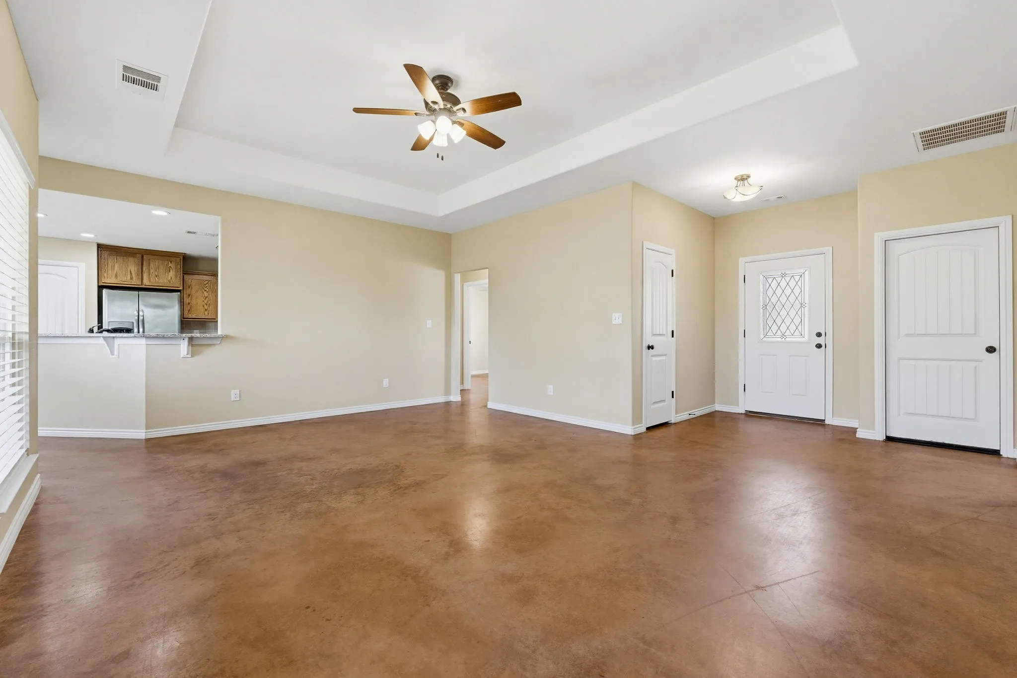 Open-concept living space featuring wood-finish flooring and a tray ceiling with a ceiling fan