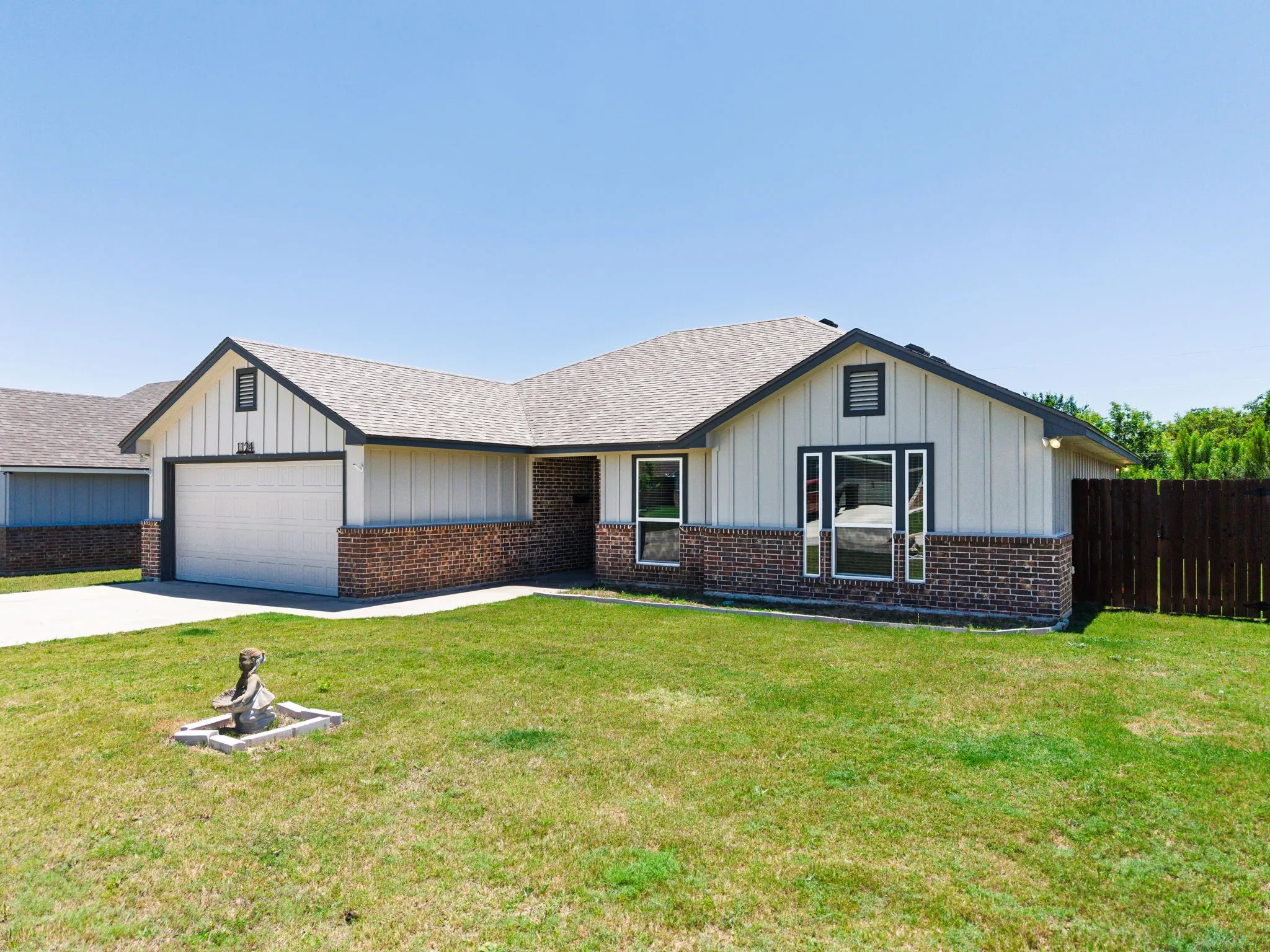 Ranch-style exterior featuring a red brick wainscoting and vertical siding