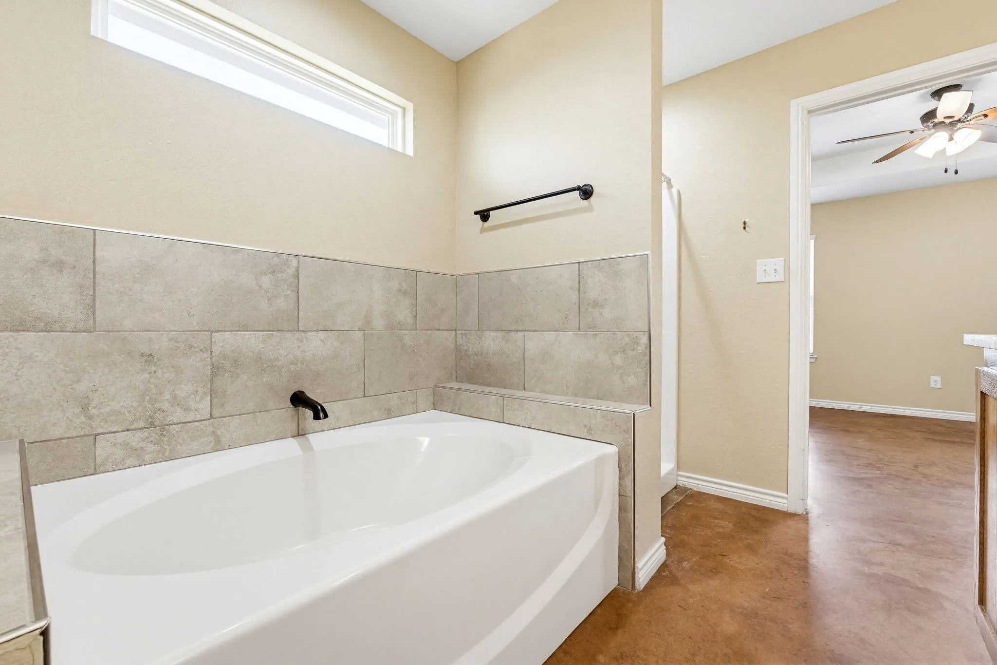 Recessed bathtub with a black wall-mounted faucet, surrounded by large format tile wainscoting