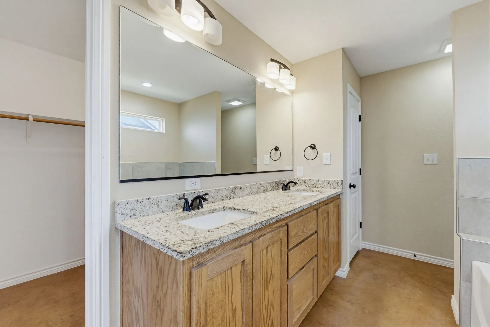 Double vanity featuring light-colored granite countertops with undermount sinks and matte black fixtures