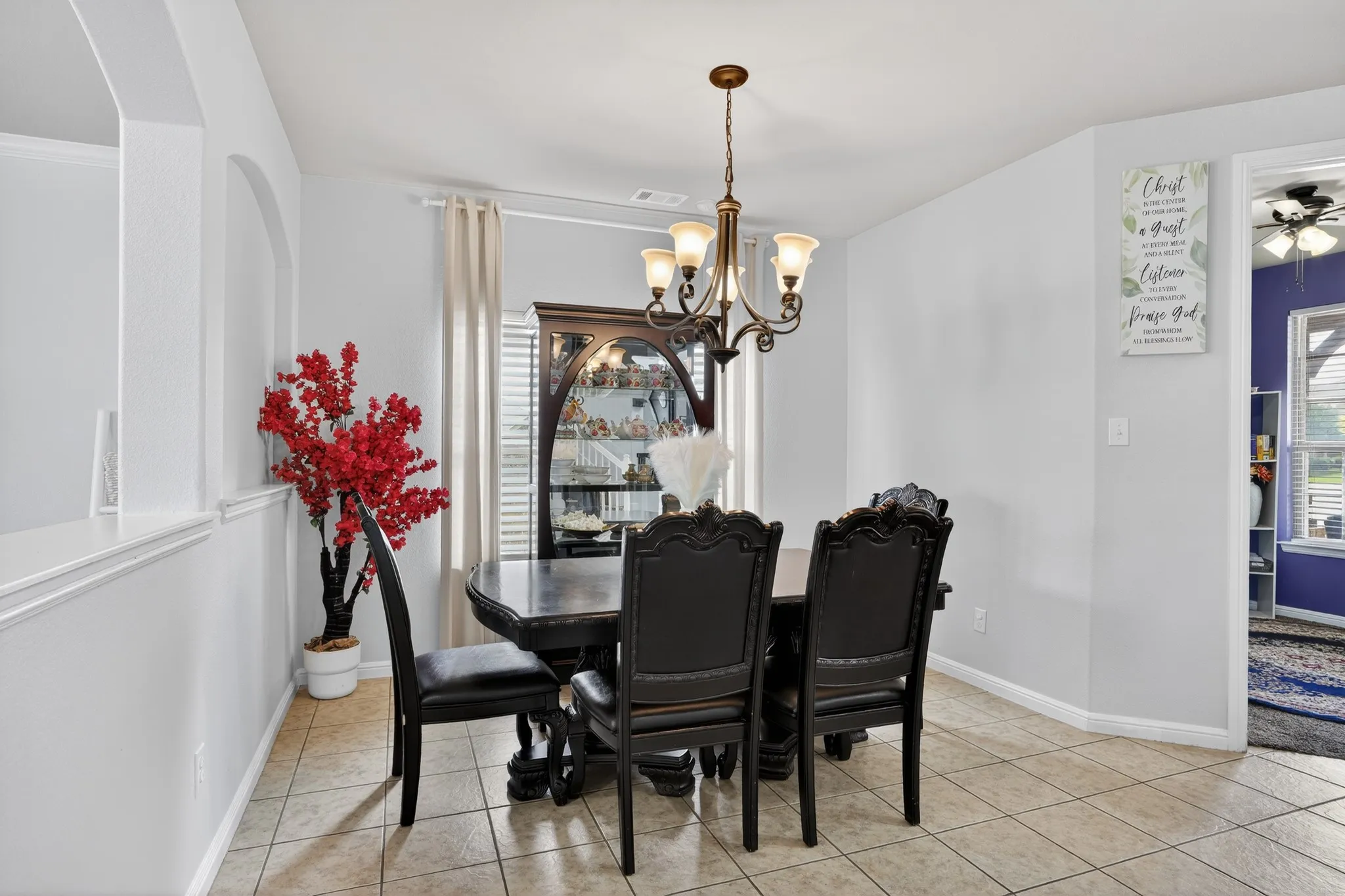 Dining area featuring tiled flooring, a decorative chandelier, and a built-in display cabinet