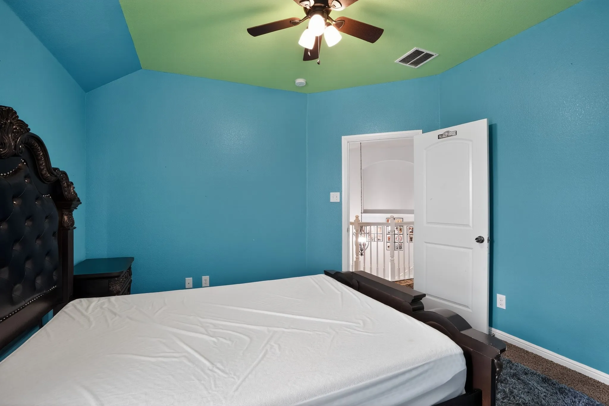 Bedroom featuring vibrant blue wall finishes and a contrasting green vaulted ceiling