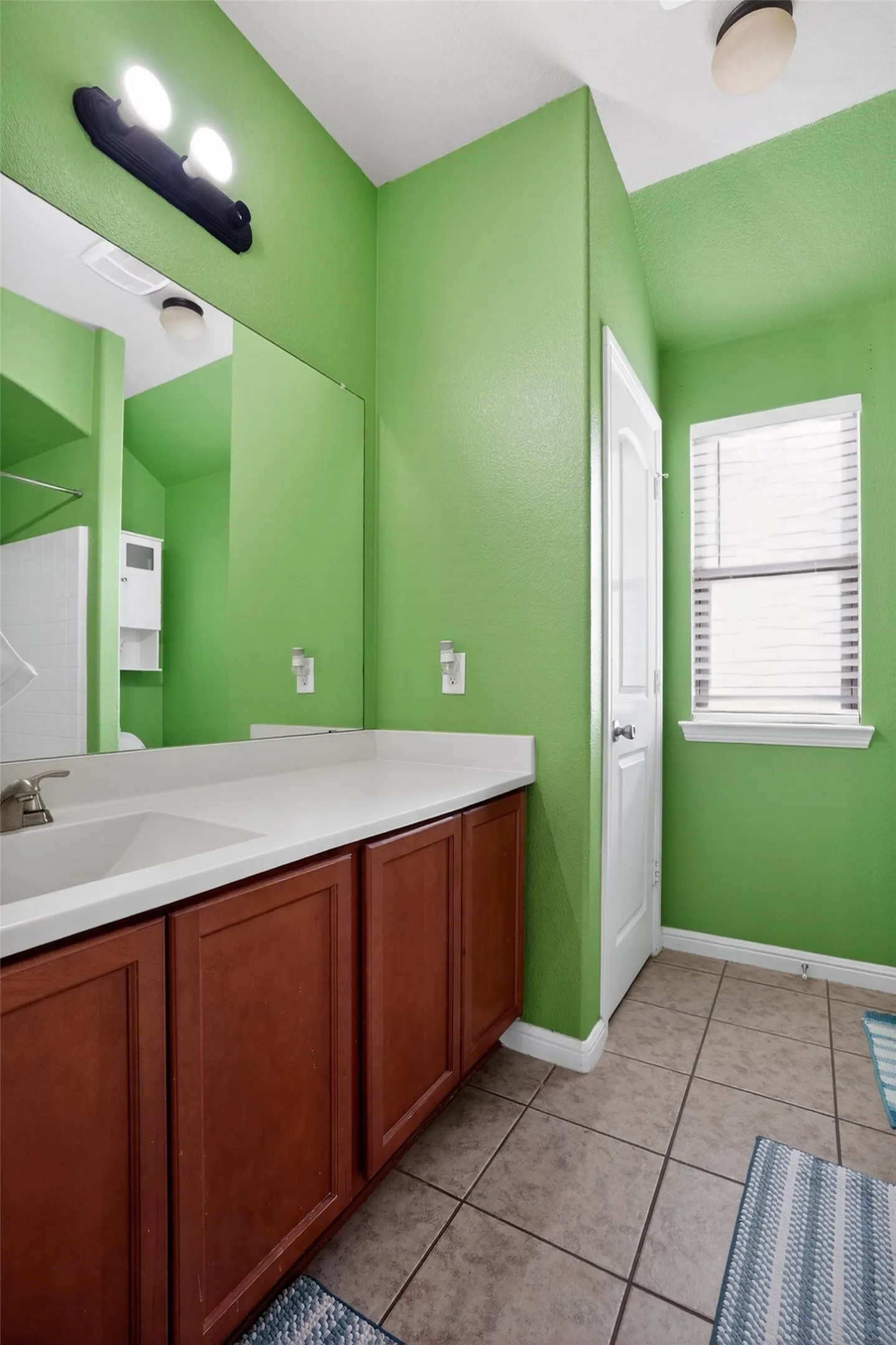 Bathroom featuring a dual vanity with wood-finish cabinetry, a white countertop, and an integrated sink