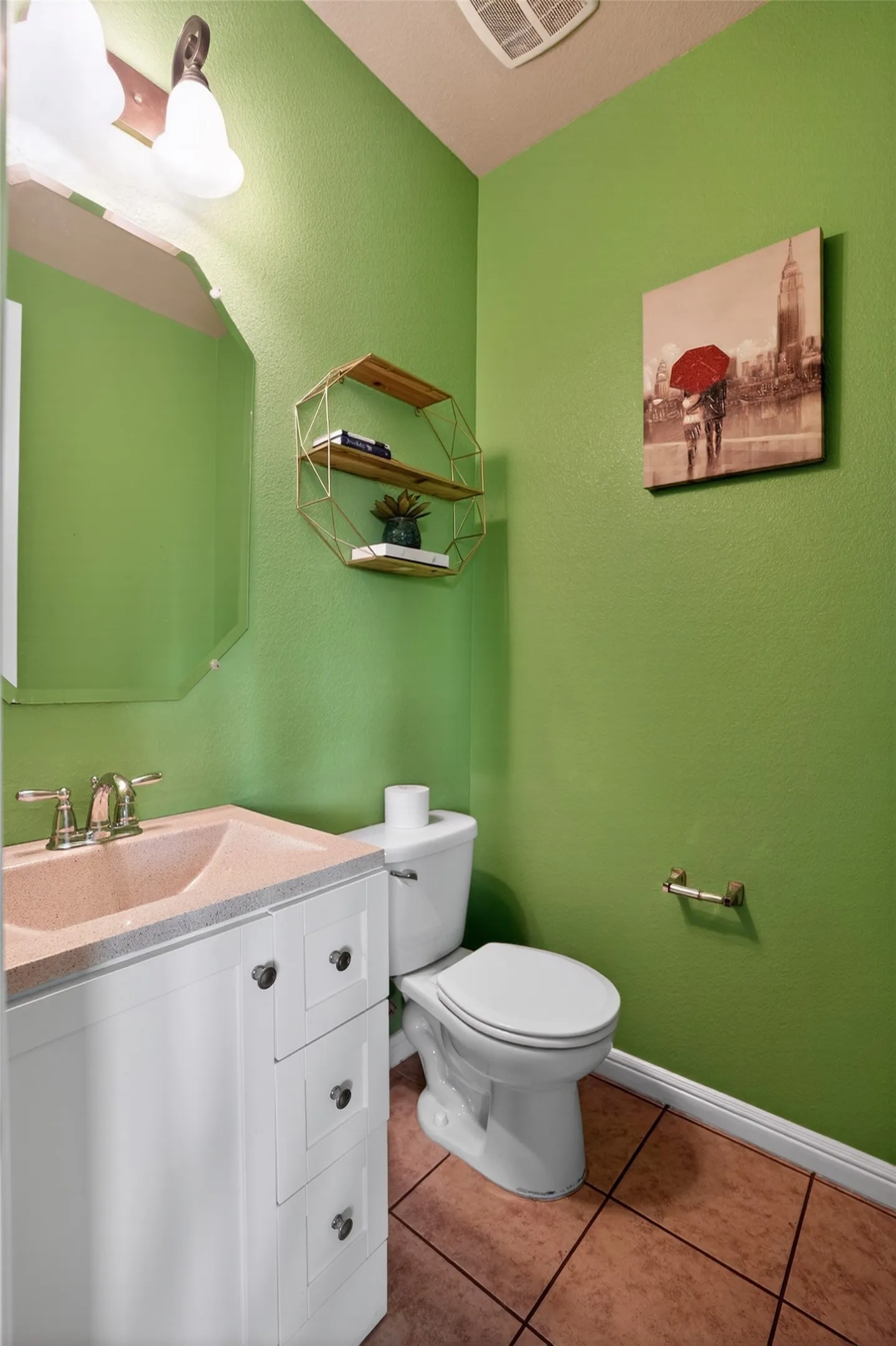 Bathroom featuring a white vanity with paneling and dark hardware, a light-toned countertop with integrated sink, a chrome faucet, and a white toilet