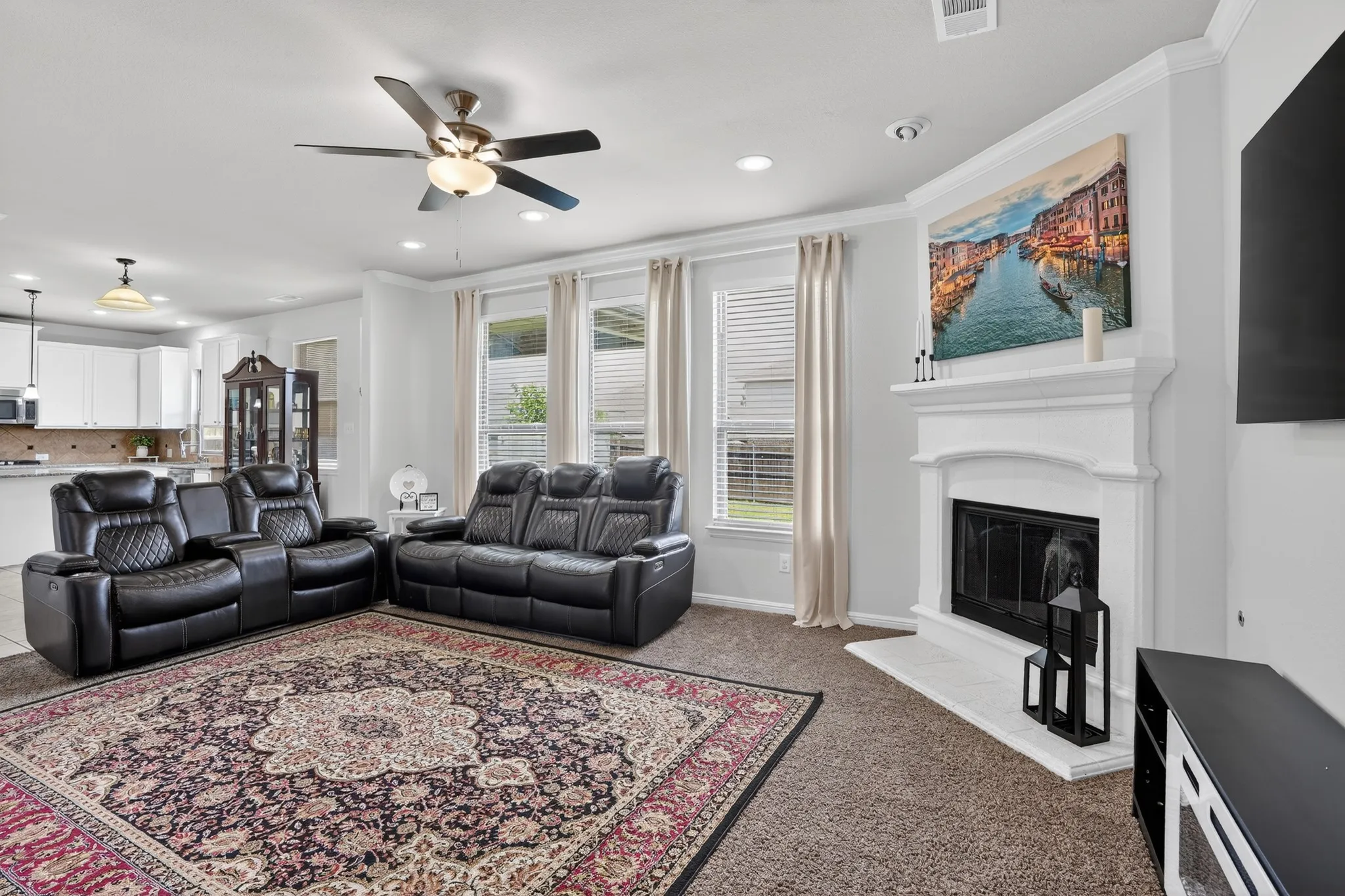 Living area featuring a central fireplace with a white mantel and hearth, recessed lighting, and a ceiling fan with integrated lighting