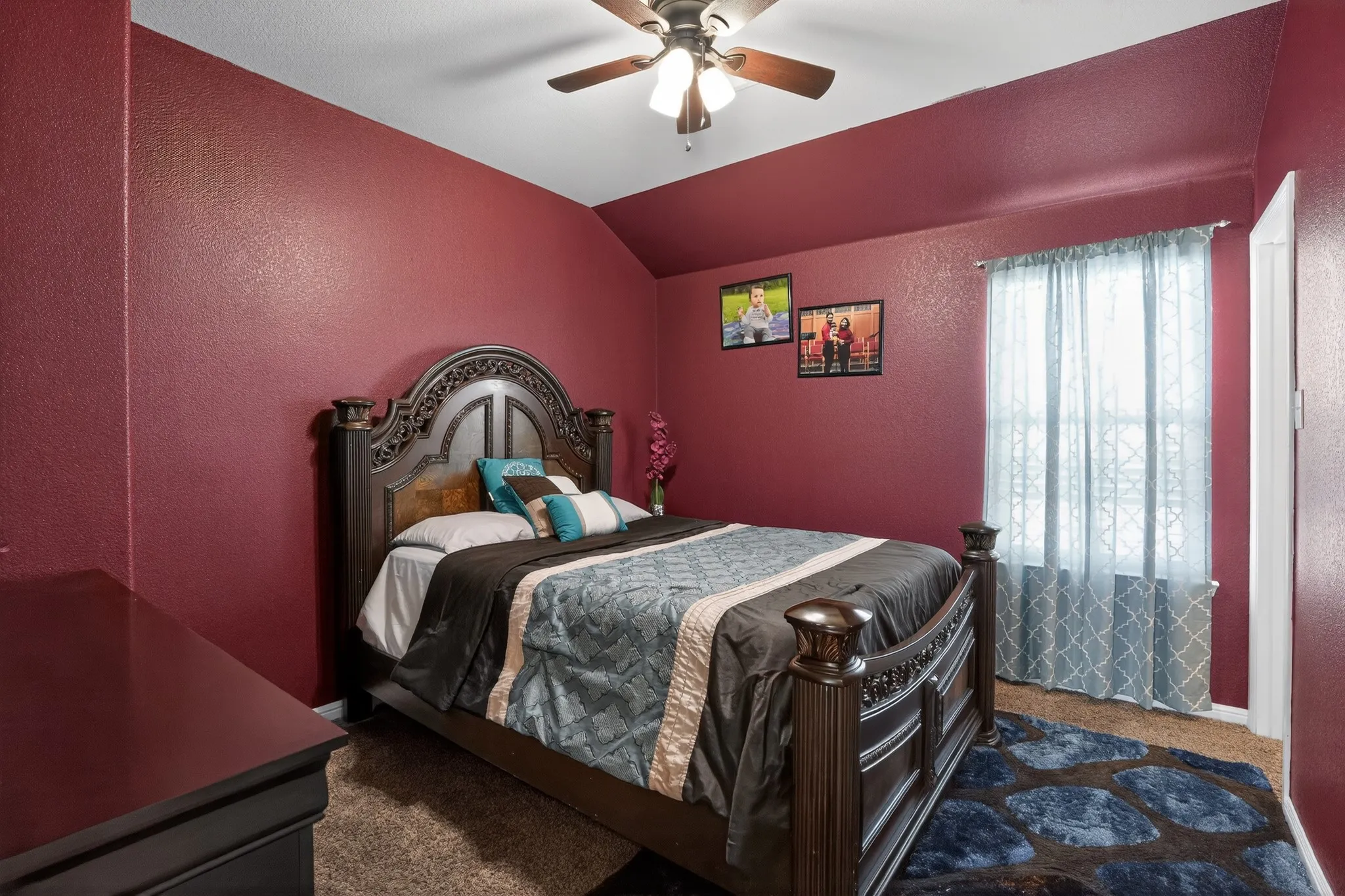 Bedroom featuring textured maroon walls and a vaulted ceiling
