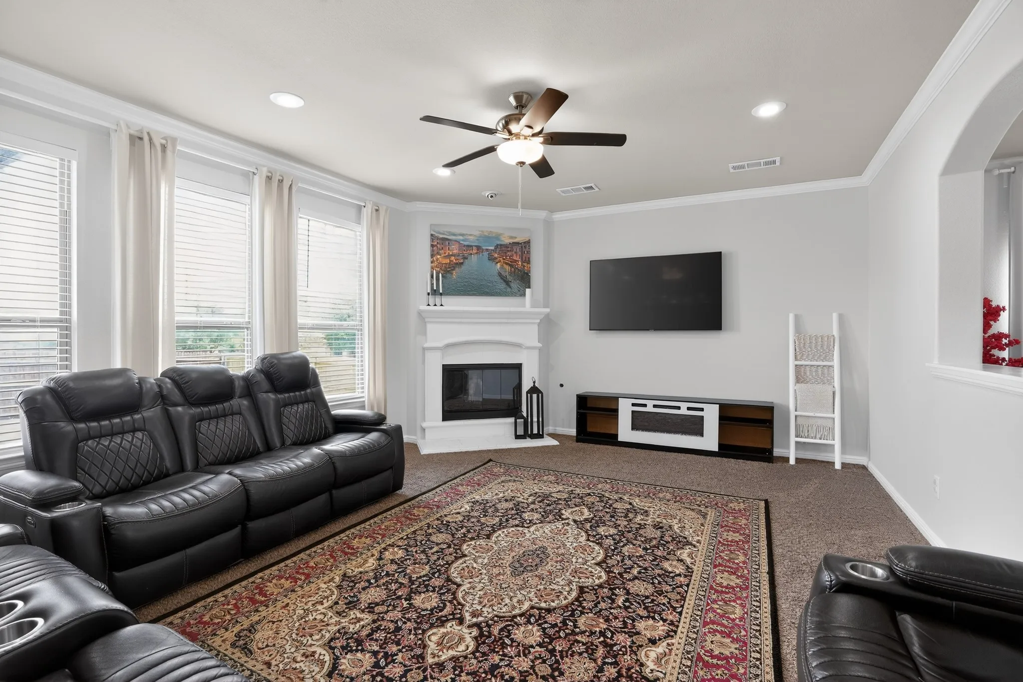 Living space featuring a corner fireplace with a white mantel, recessed lighting, and a ceiling fan