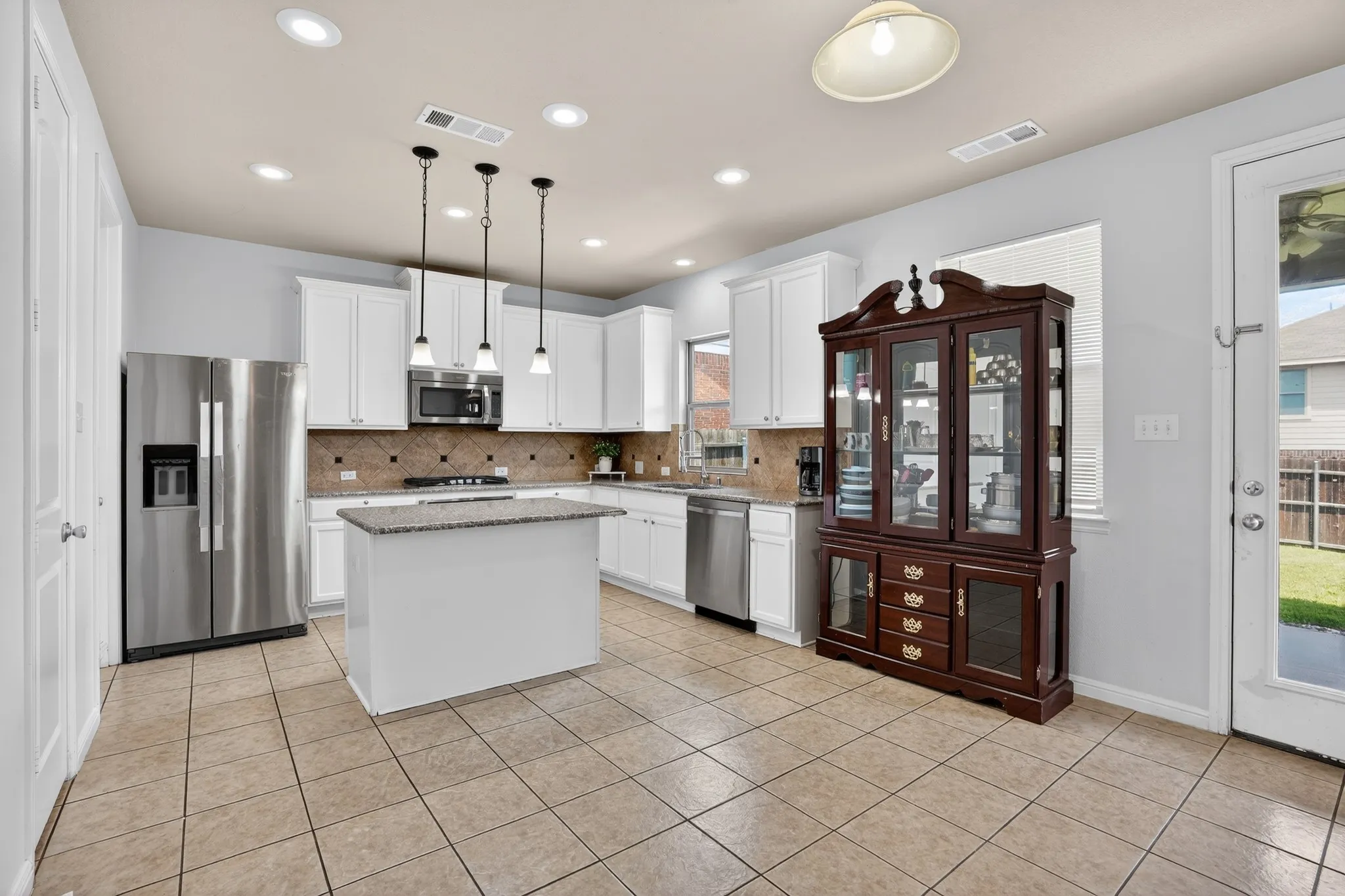 Kitchen featuring white cabinetry, stainless steel appliances, a center island with a stone countertop, and tile flooring