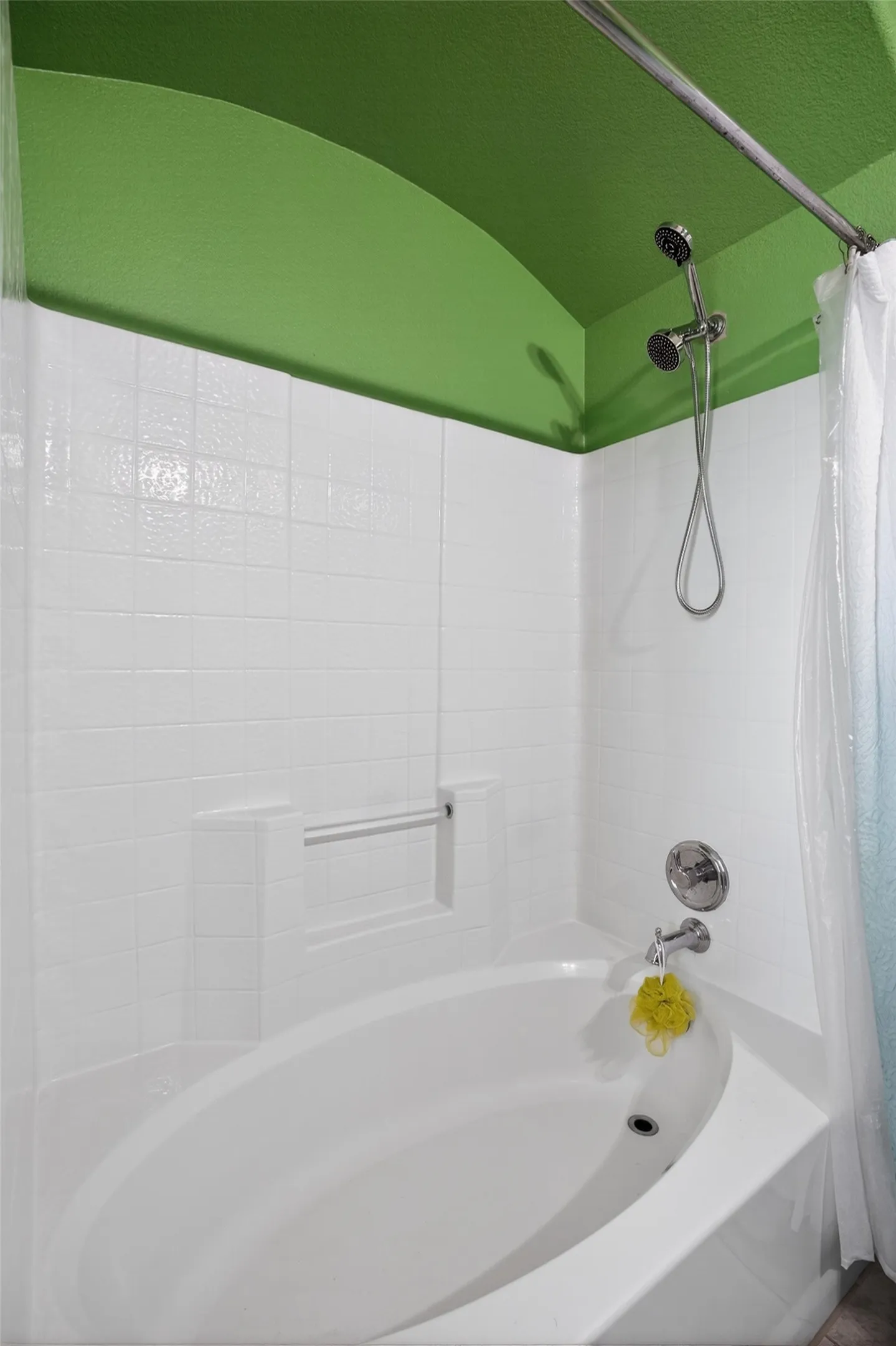 Built-in bathtub with white tile surround, chrome fixtures, and a curved shower rod